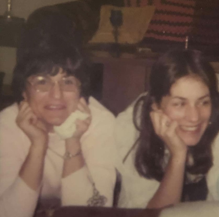 A photo of two women sitting next to each other with their hands resting on their cheeks.