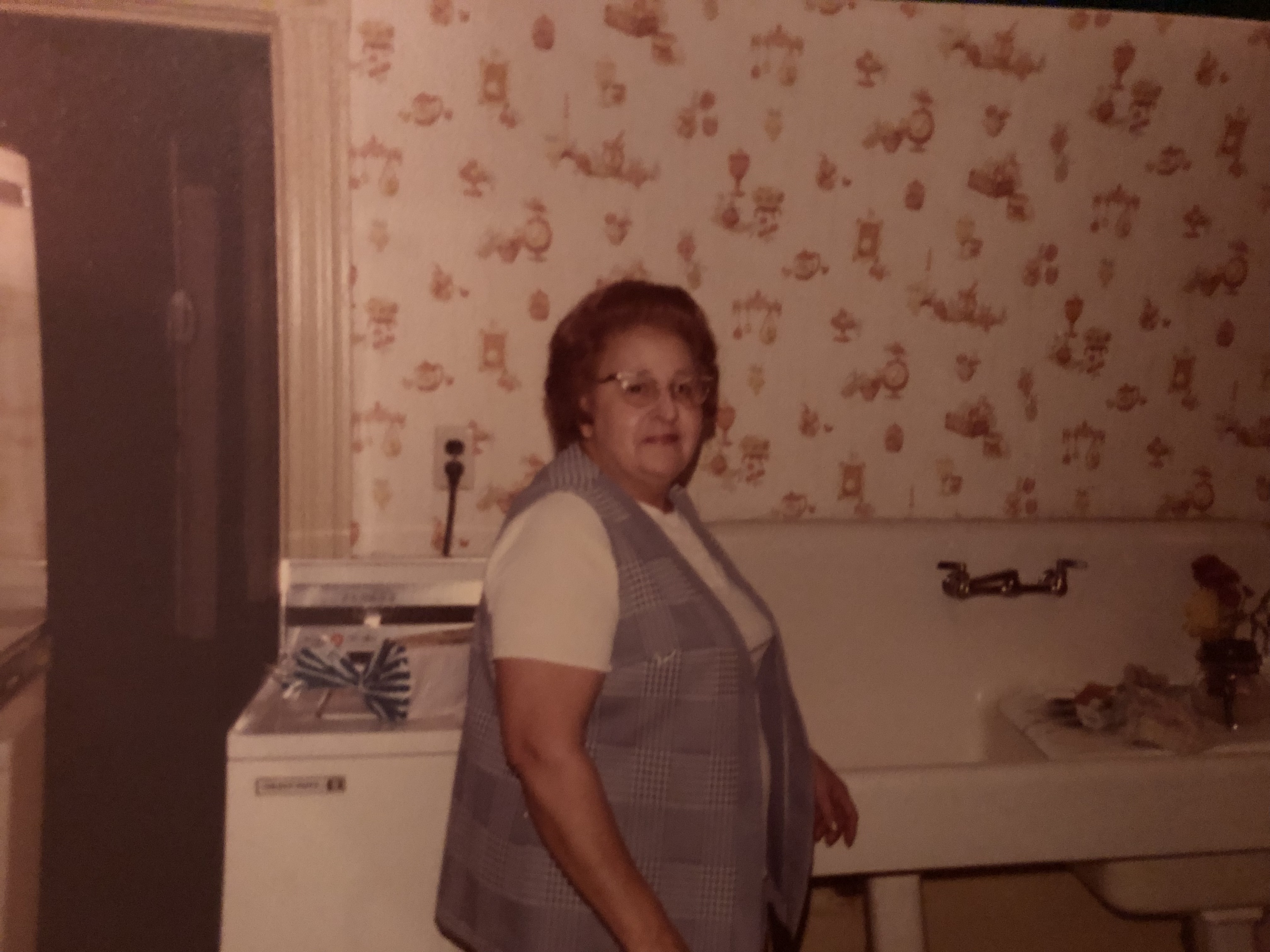 A photo of a woman standing in front of a sink.