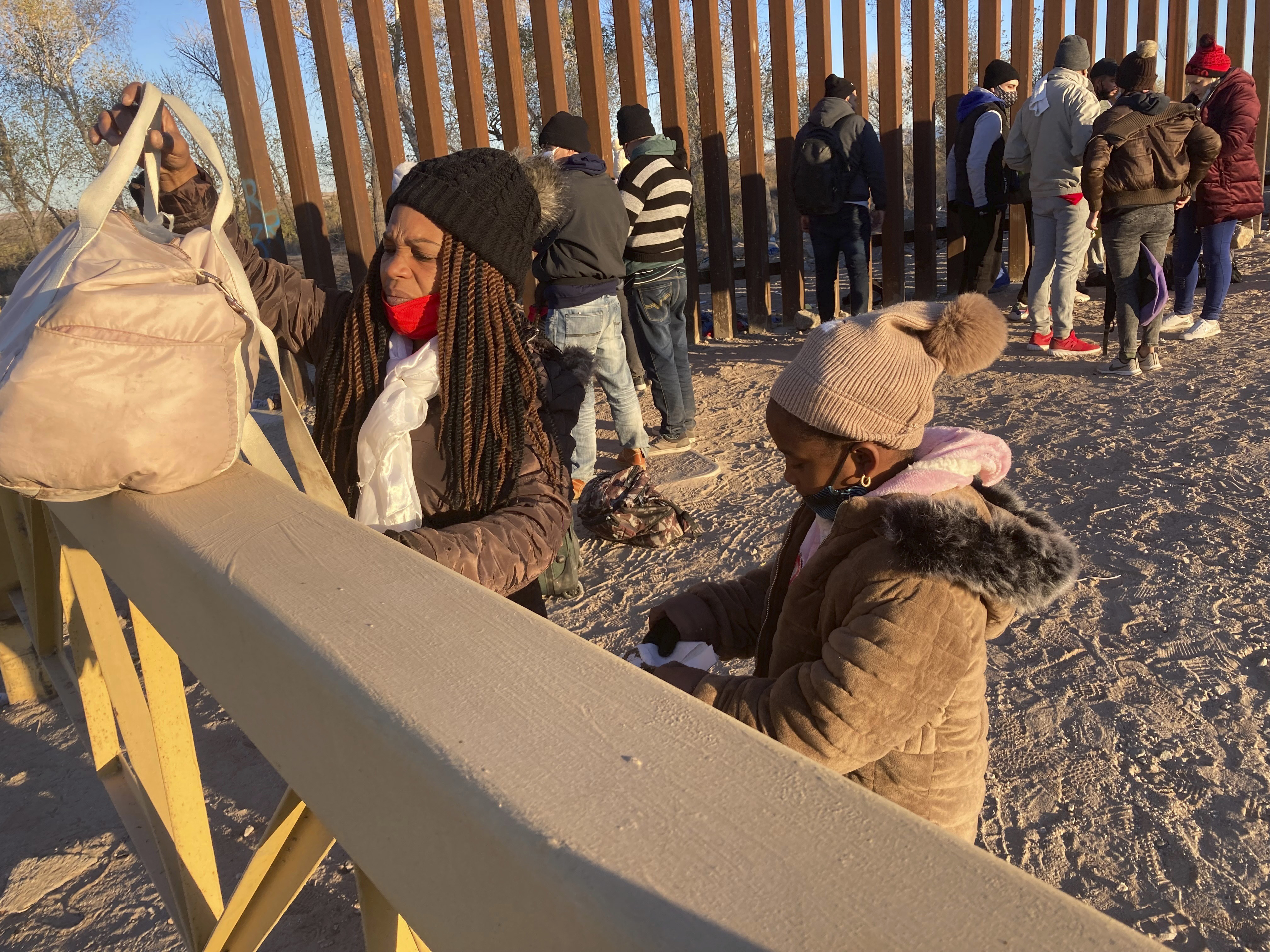 A Cuban woman and her daughter wait in line to be escorted to a Border Patrol van for processing in Yuma, Ariz.