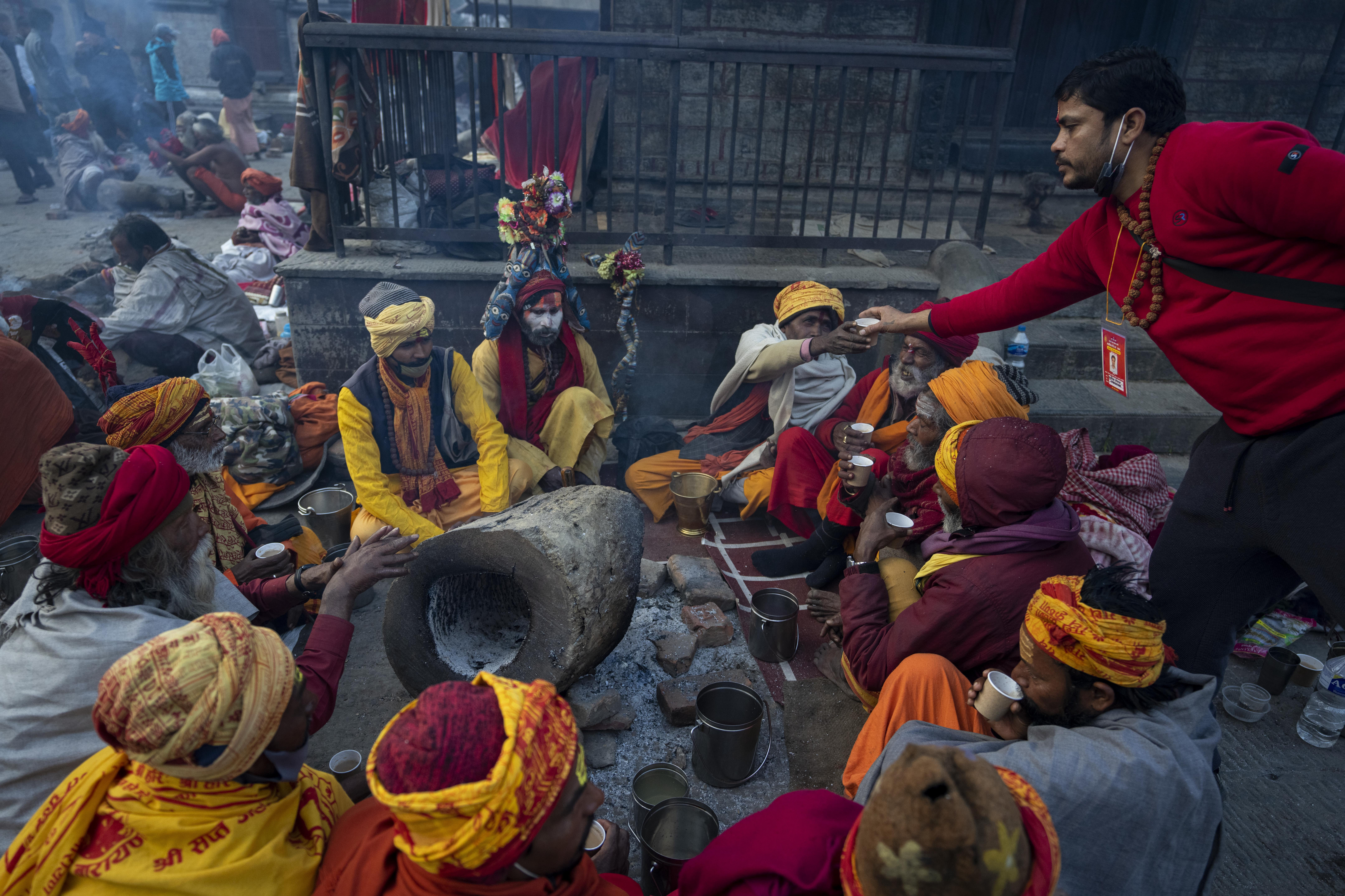 A volunteer offers tea to holy men