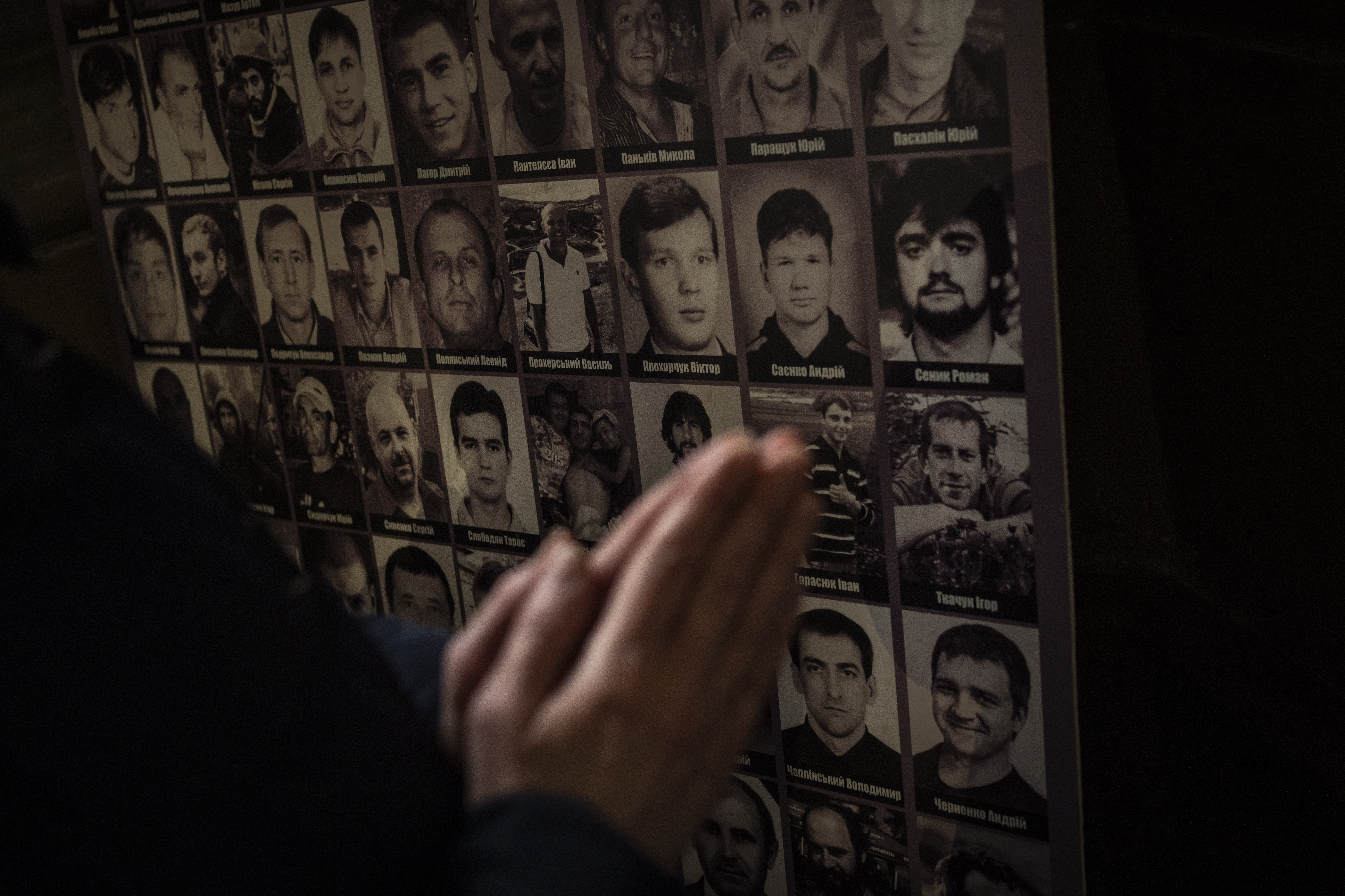 A Christian worshipper prays in front of pictures of fallen soldiers at the Saints Peter and Paul Garrison Church in Lviv
