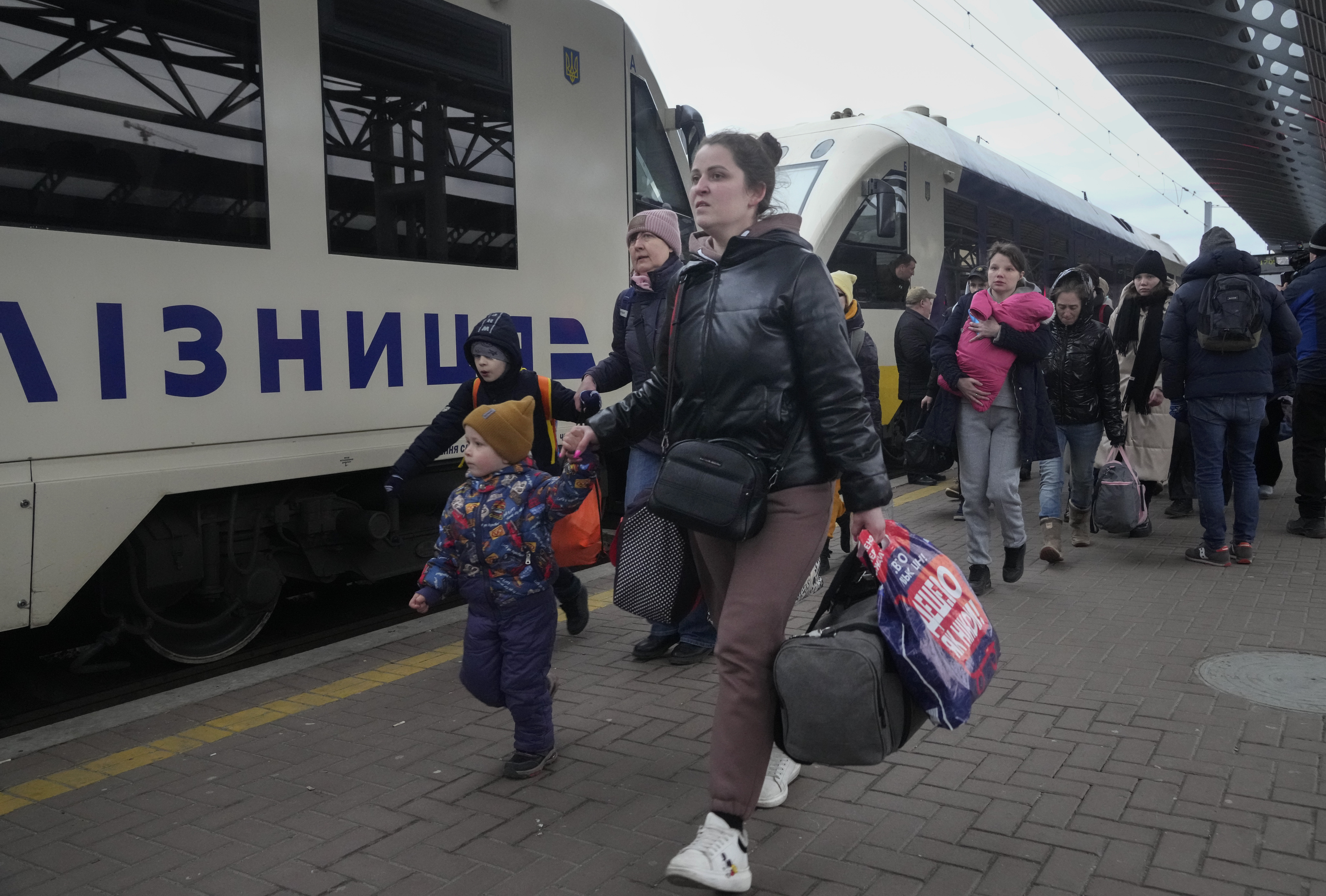 Parents accompany children and teenagers as they board a train after leaving Kyiv's Central Children's Hospital, following its evacuation, in Kyiv,