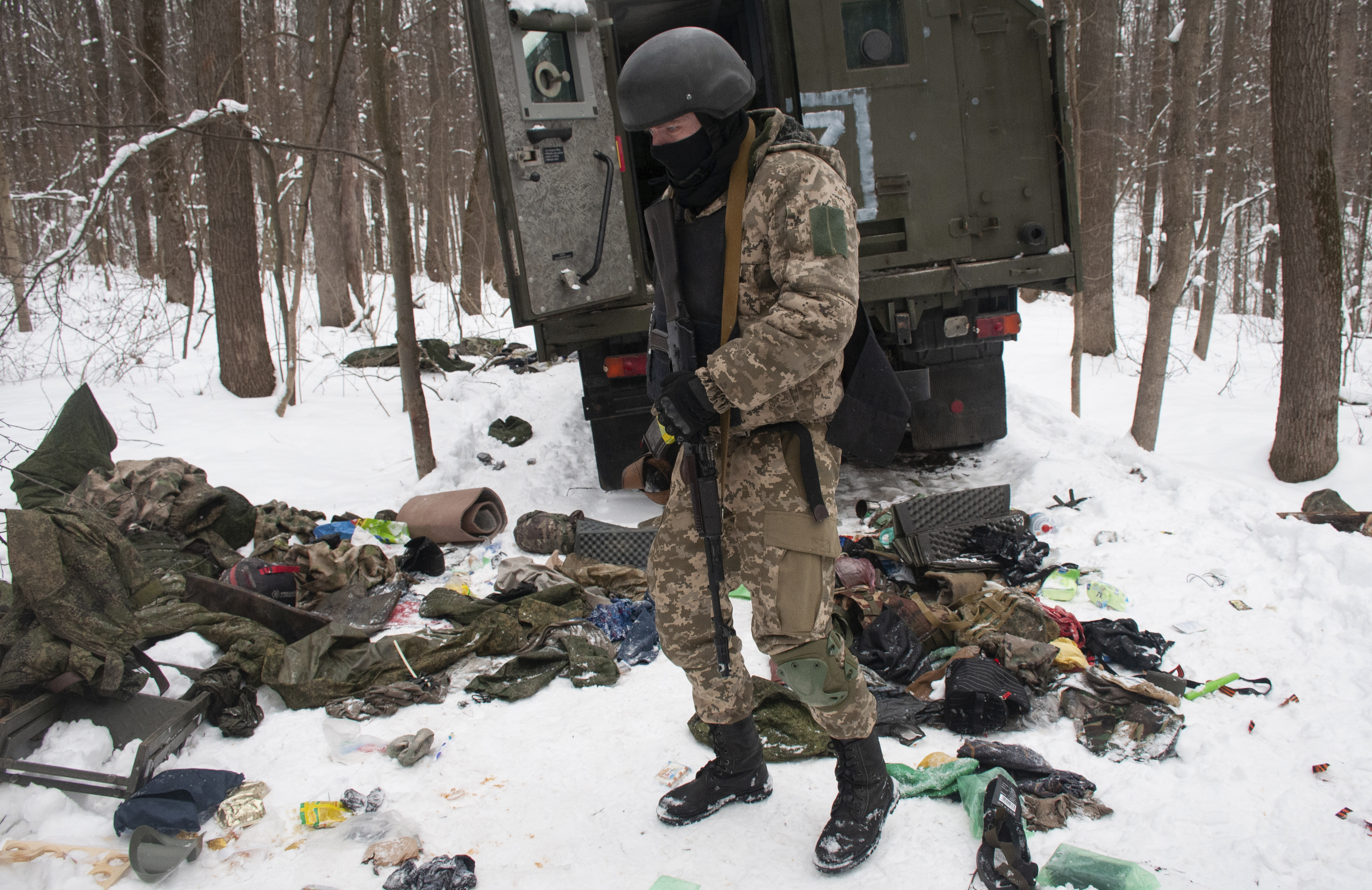 A photo of a Ukrainian soldier assessing the debris of a damaged military vehicle.