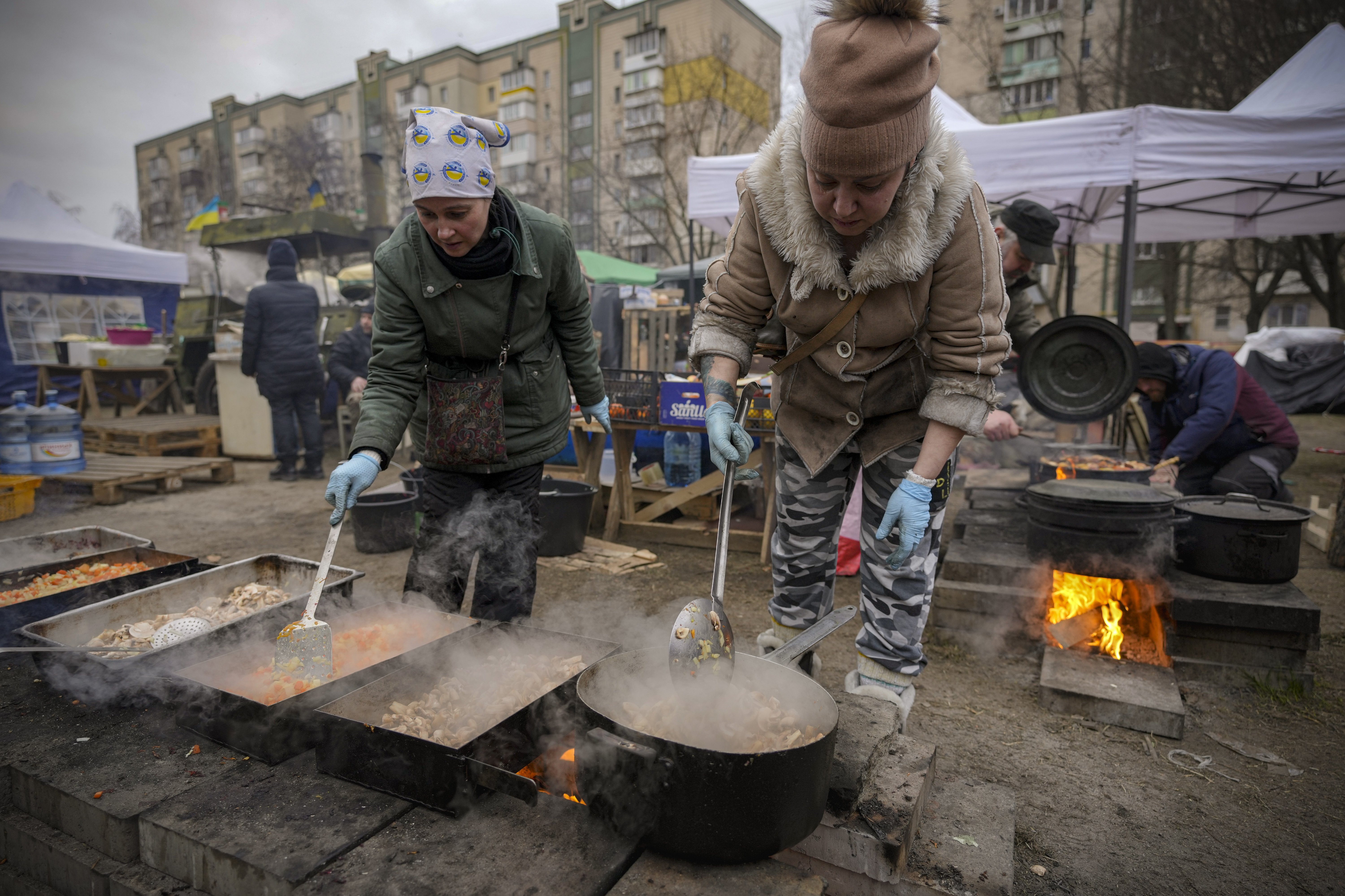 People cook outdoors for Ukrainian servicemen and civil defense members serving in Kyiv