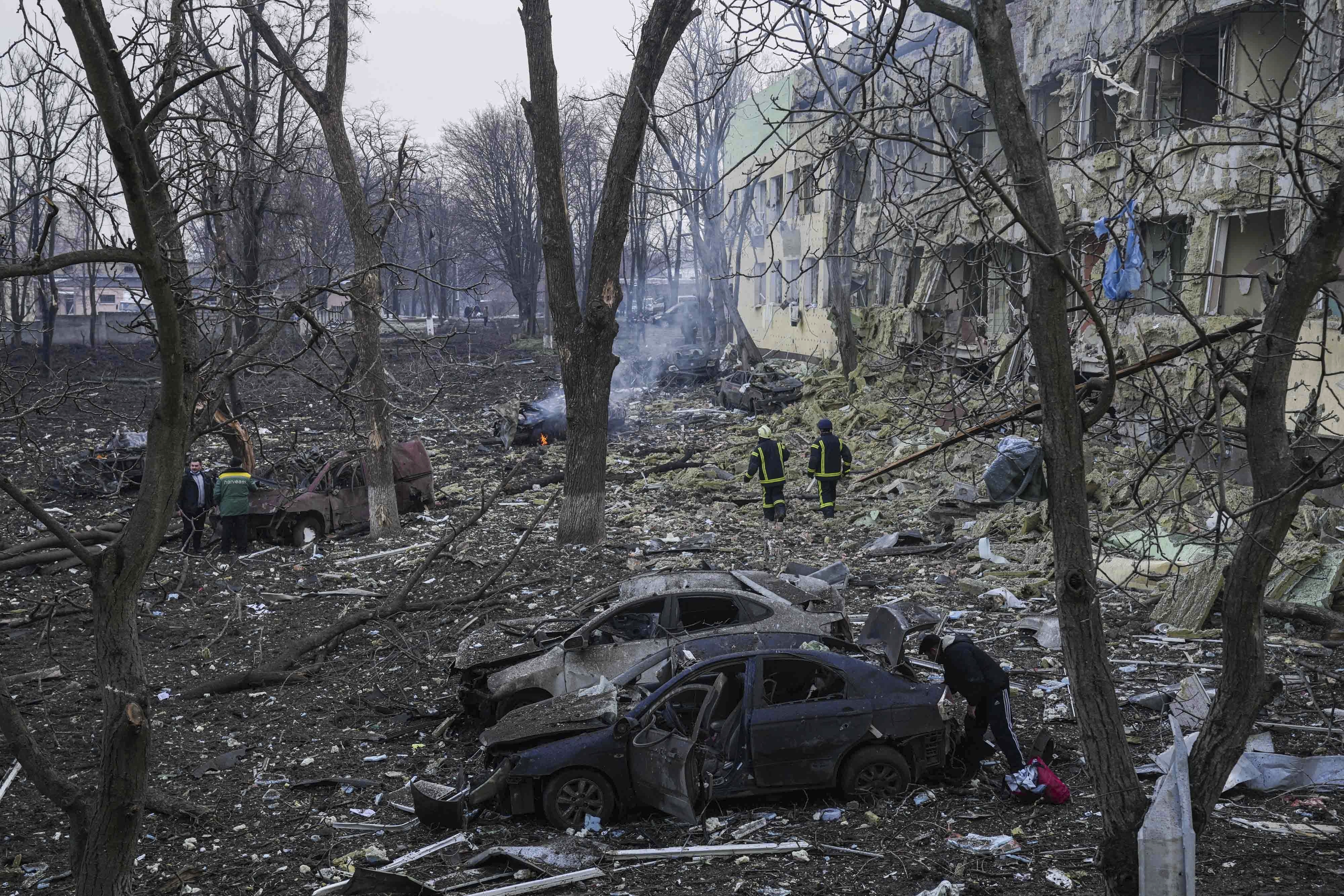 Ukrainian emergency employees work at the side of the damaged by shelling maternity hospital in Mariupol