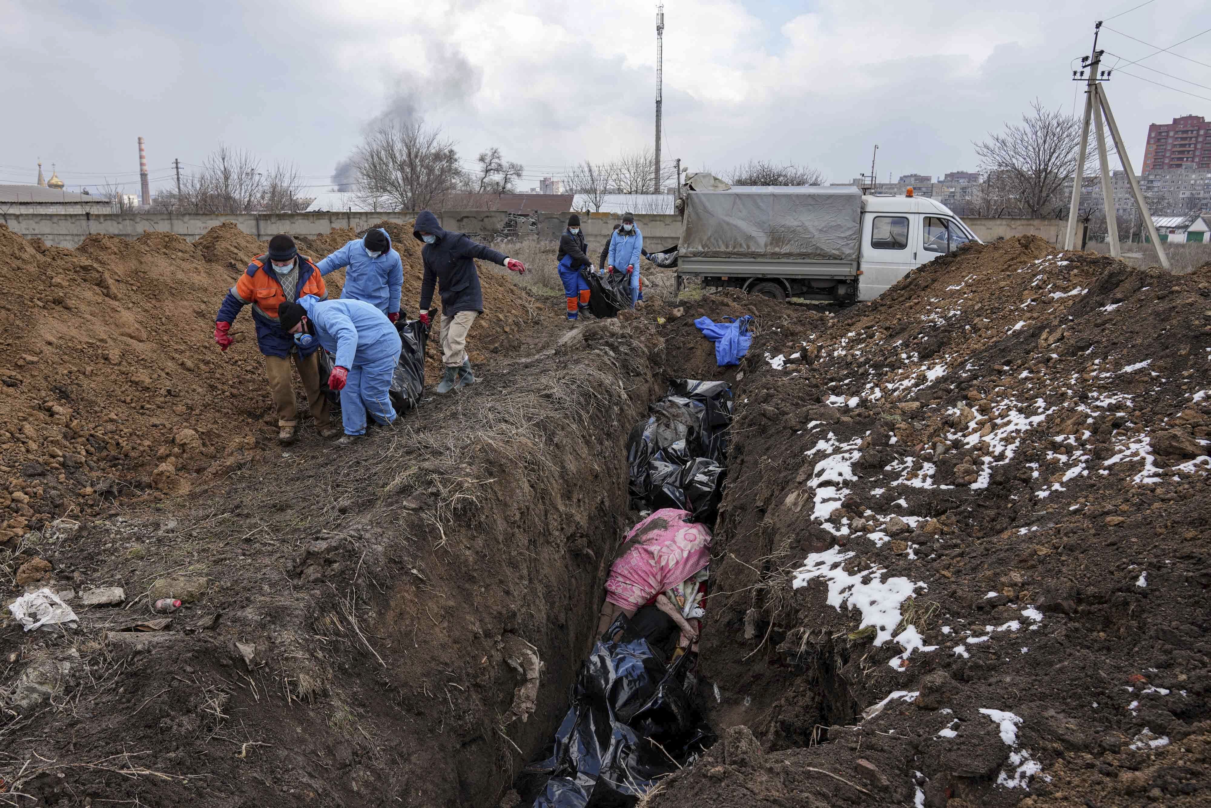 Dead bodies are seen being put into a mass grave on the outskirts of Mariupol