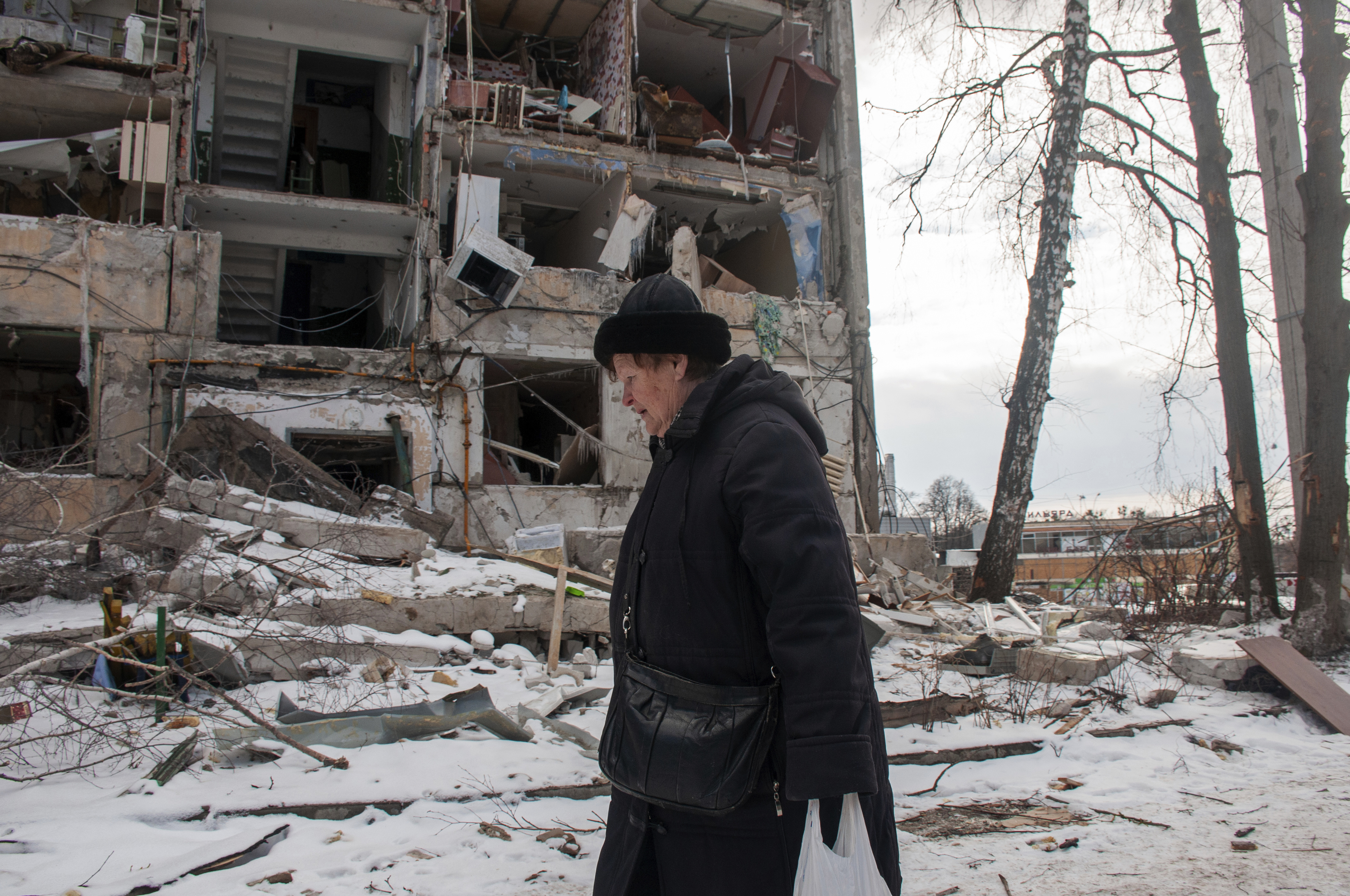 A woman walks past building damaged by shelling, in Kharkiv,