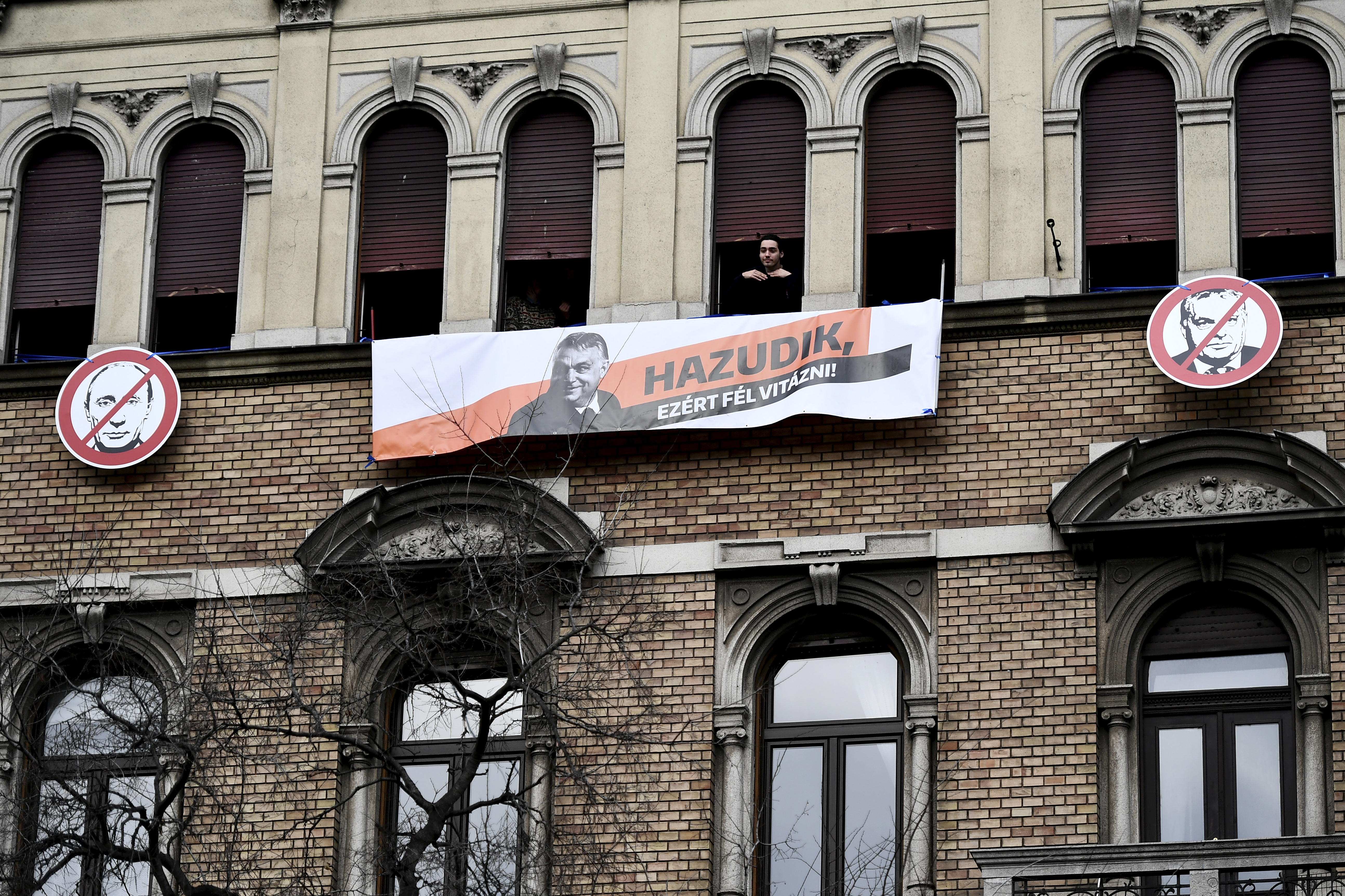 A man looks on from a window as thousands of supporters of Hungary's right-wing populist prime minister, Viktor Orban