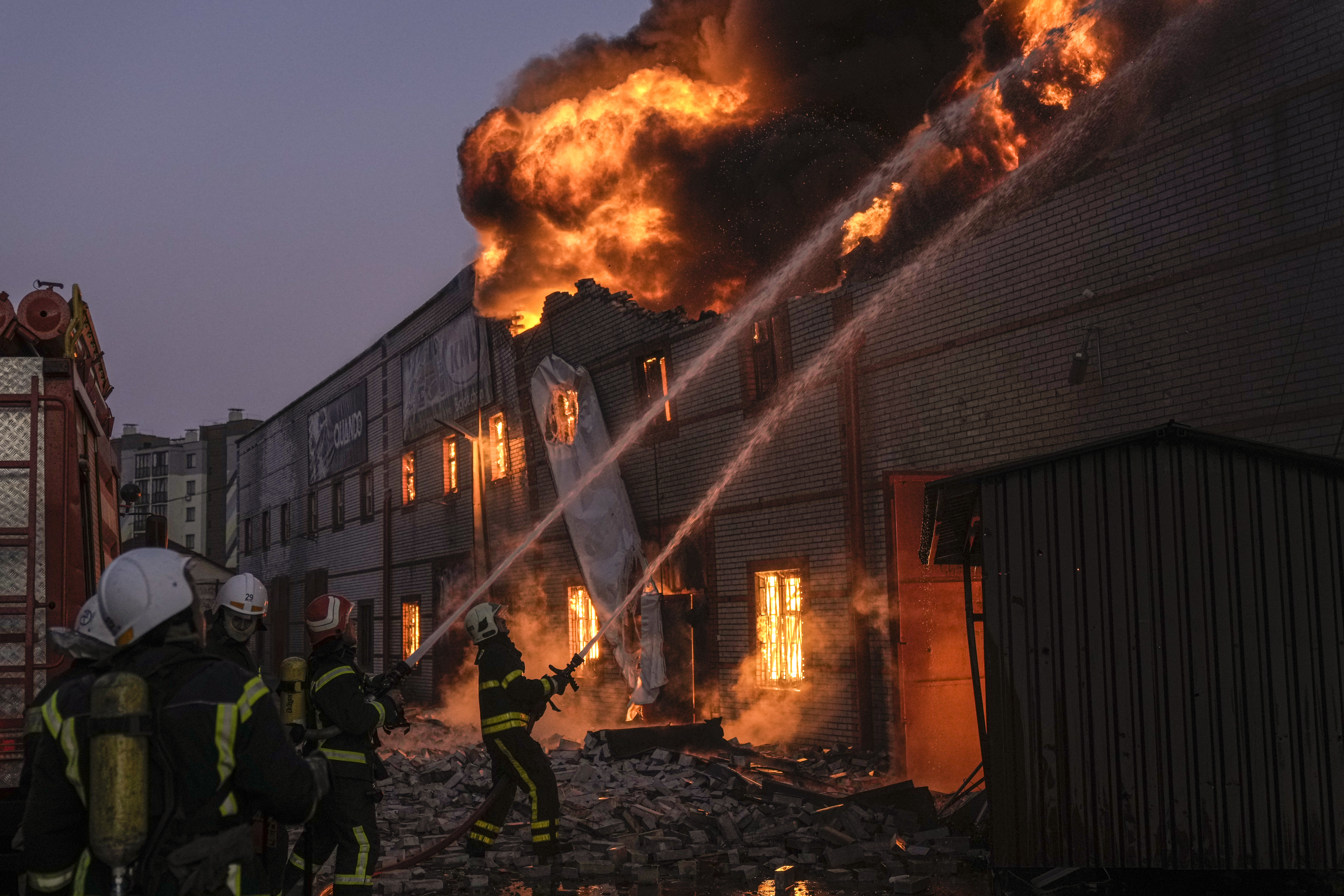 Ukrainian firefighters extinguish a blaze at a warehouse after a bombing in Kyiv