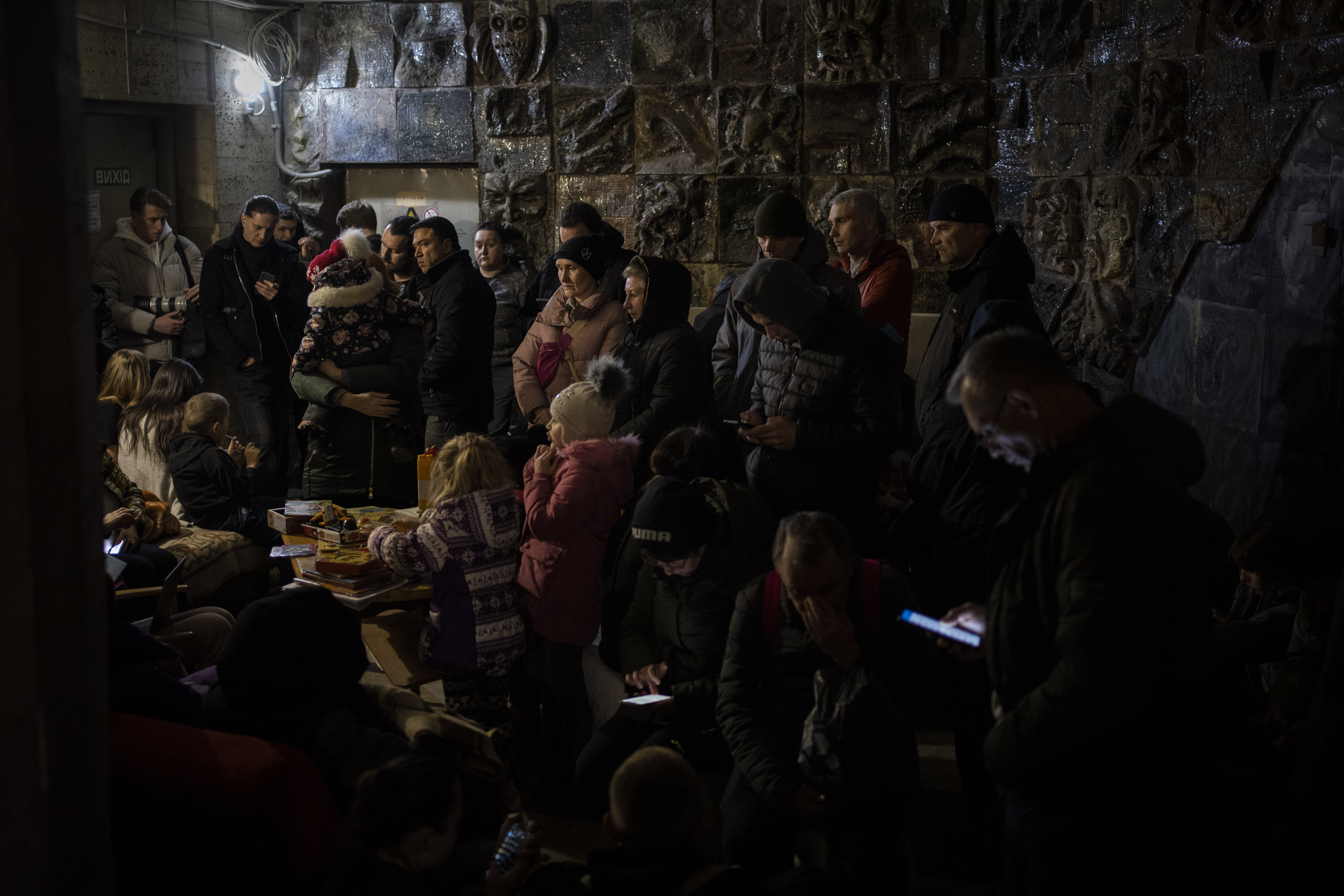 People gather in a basement, used as a bomb shelter, during an air raid in Lviv