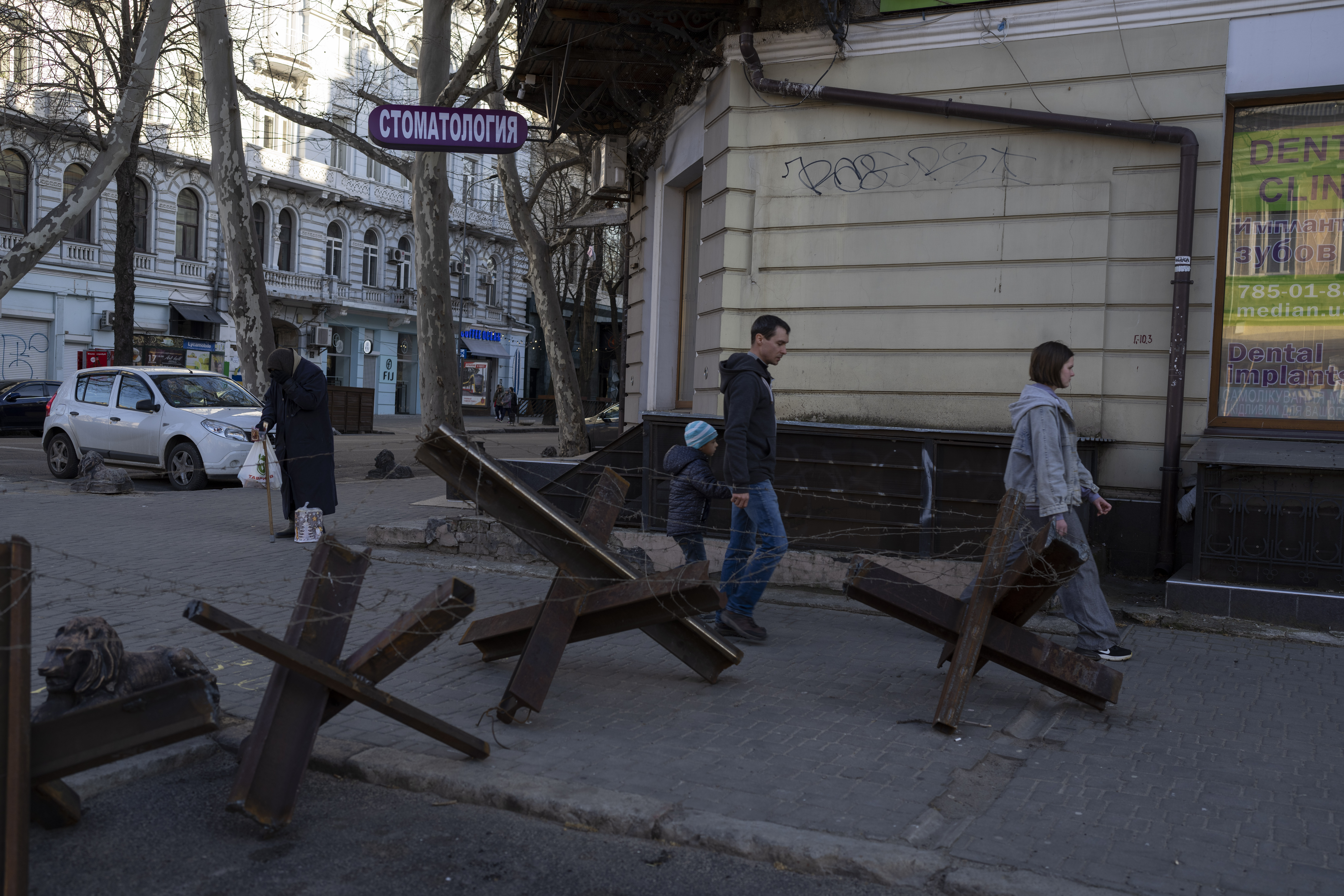 A family walks next to anti- tank barricades in Odesa