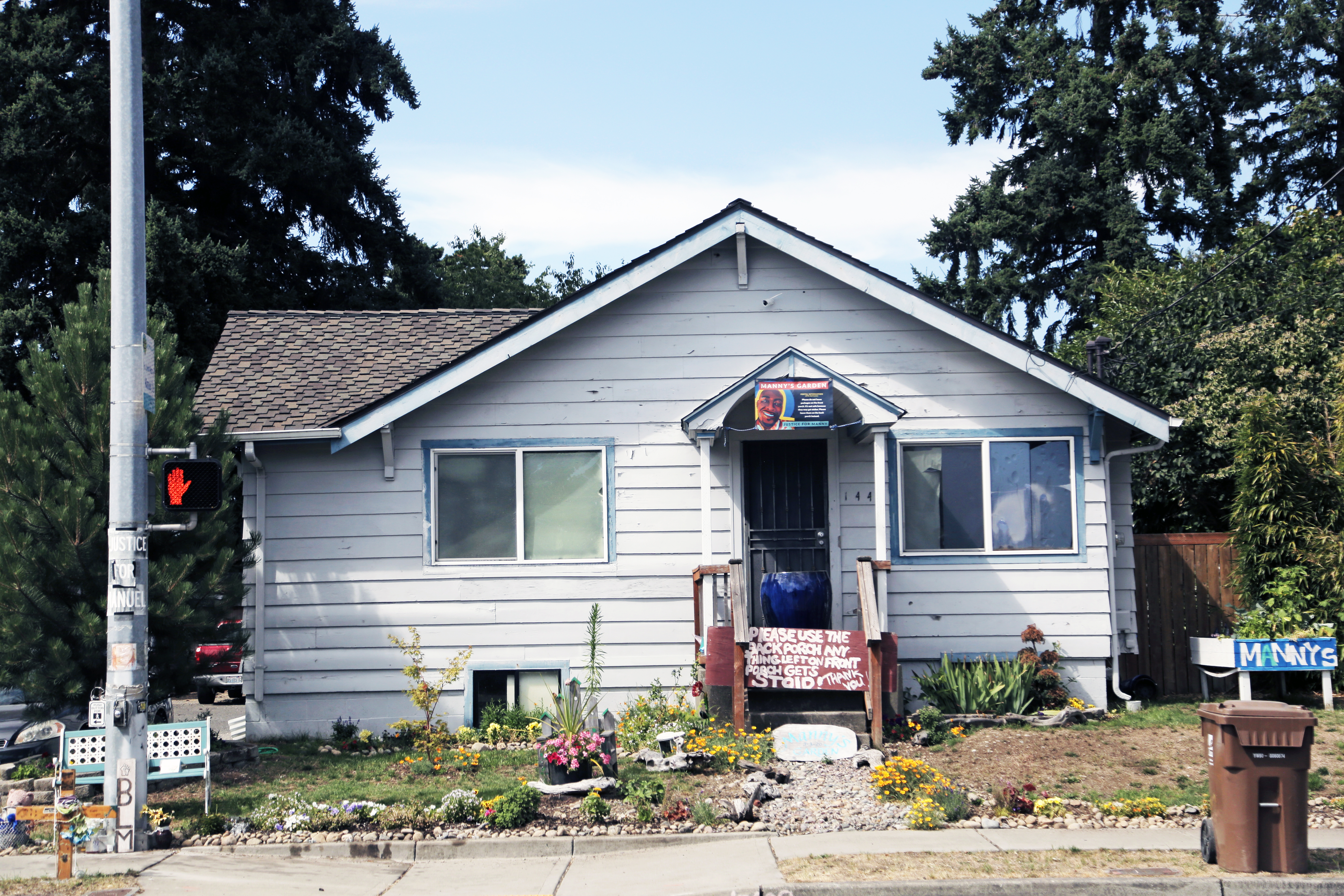 A vacant single-storey white house with a small garden in front of it