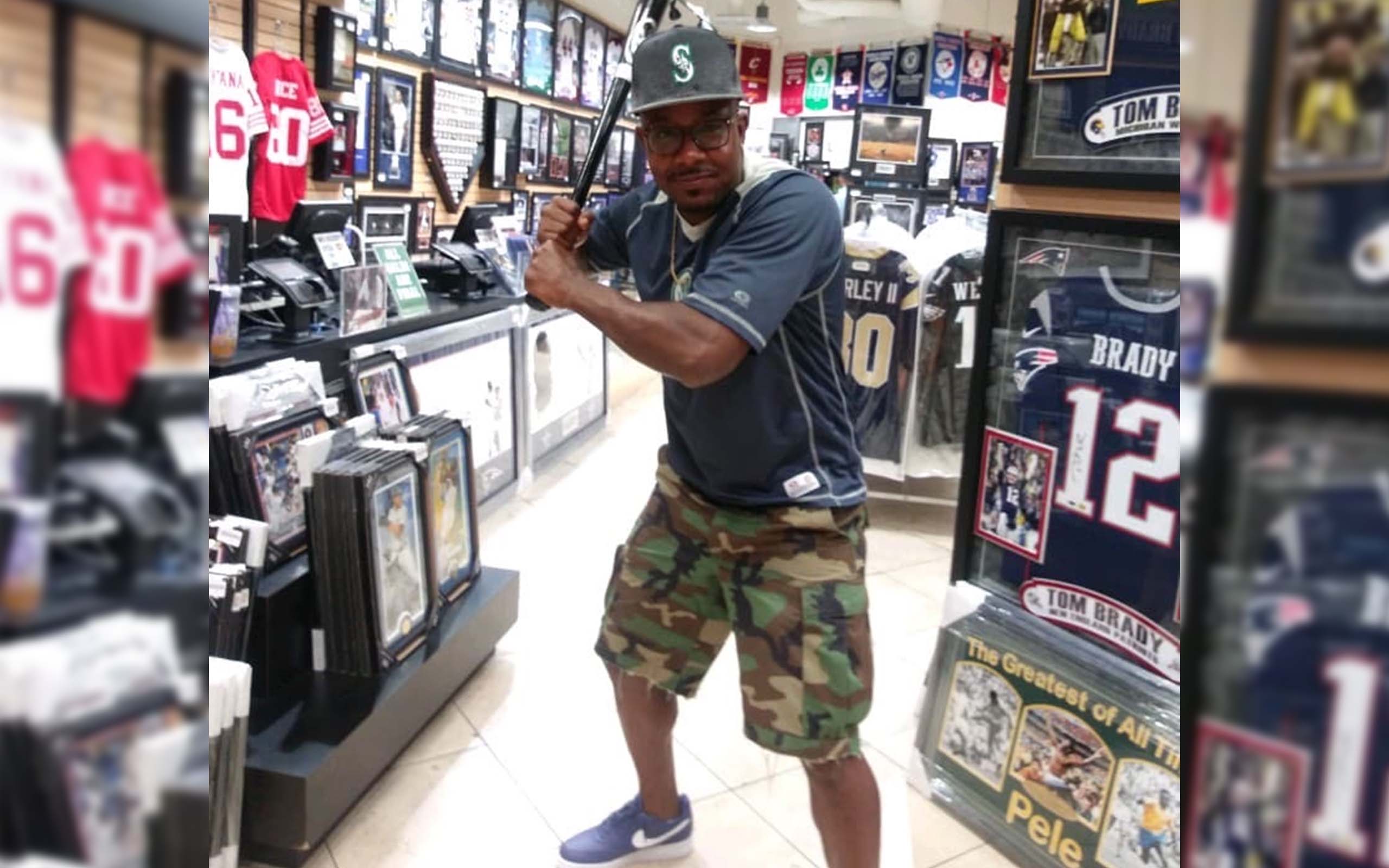 A photograph of Manuel Ellis in a shop posing with a baseball bat