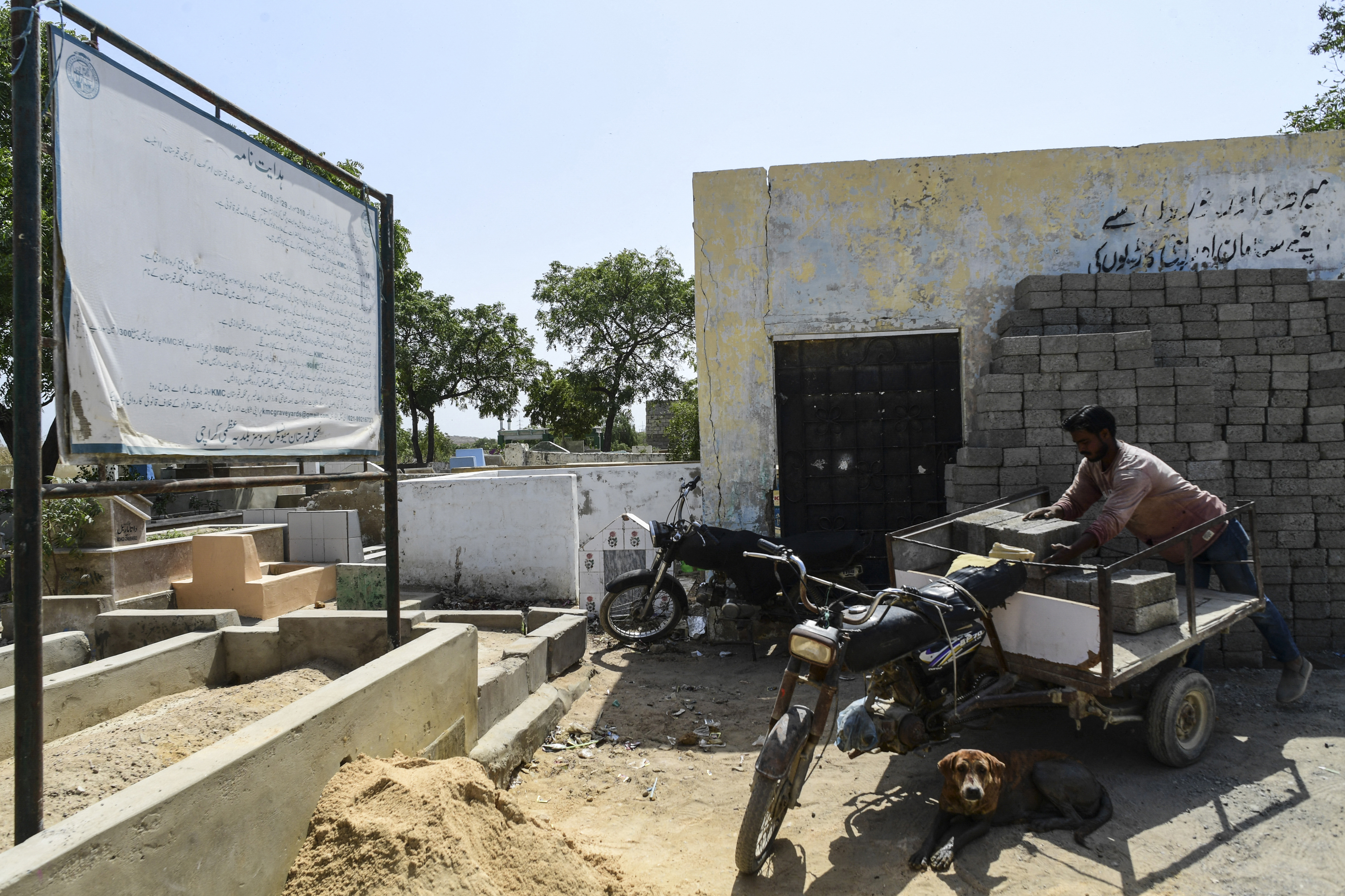 a labourer unloads bricks at the Korangi graveyard