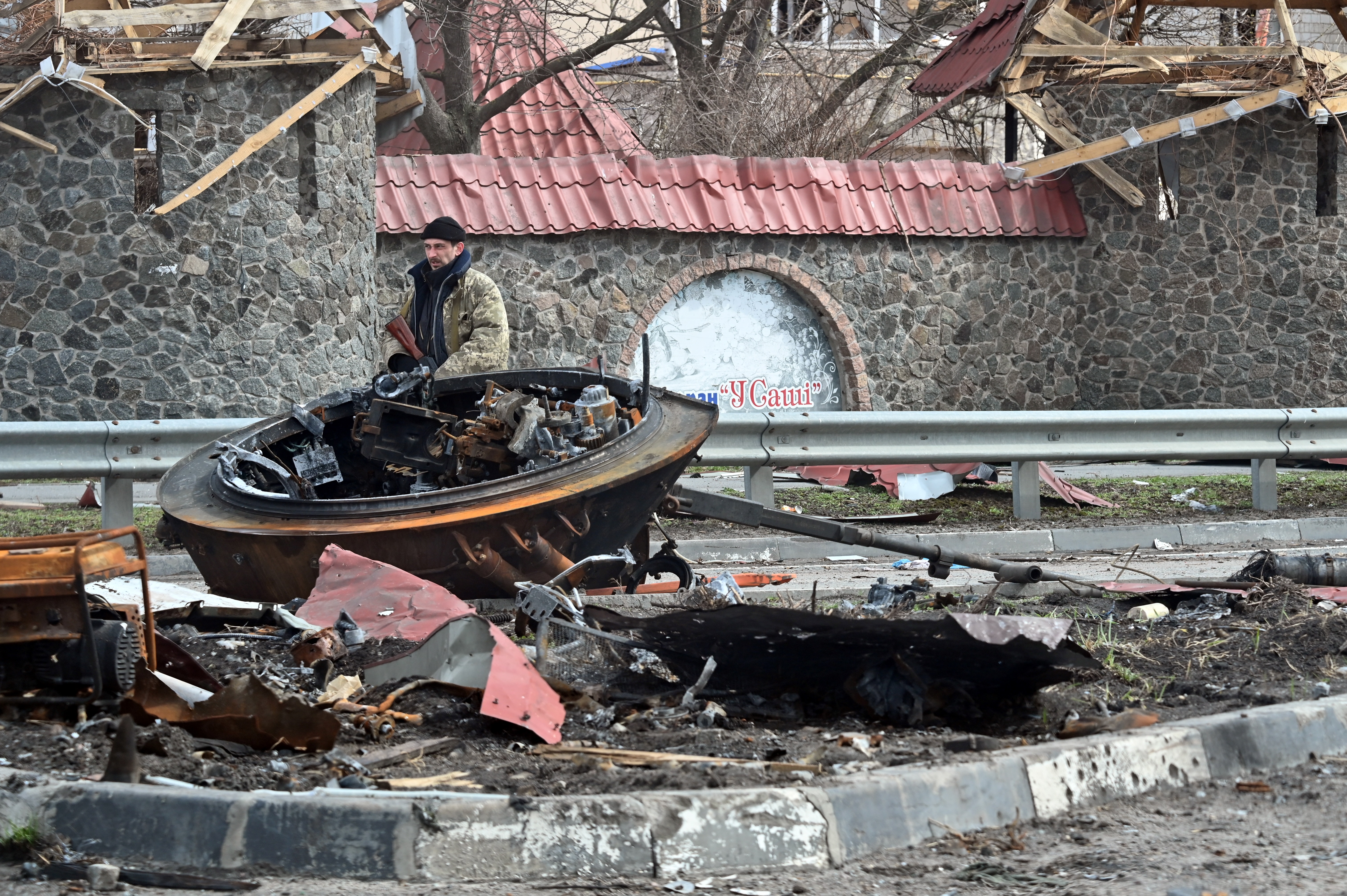 A Ukrainian territorial defence serviceman walks past a destroyed Russian armoured personnel carrier