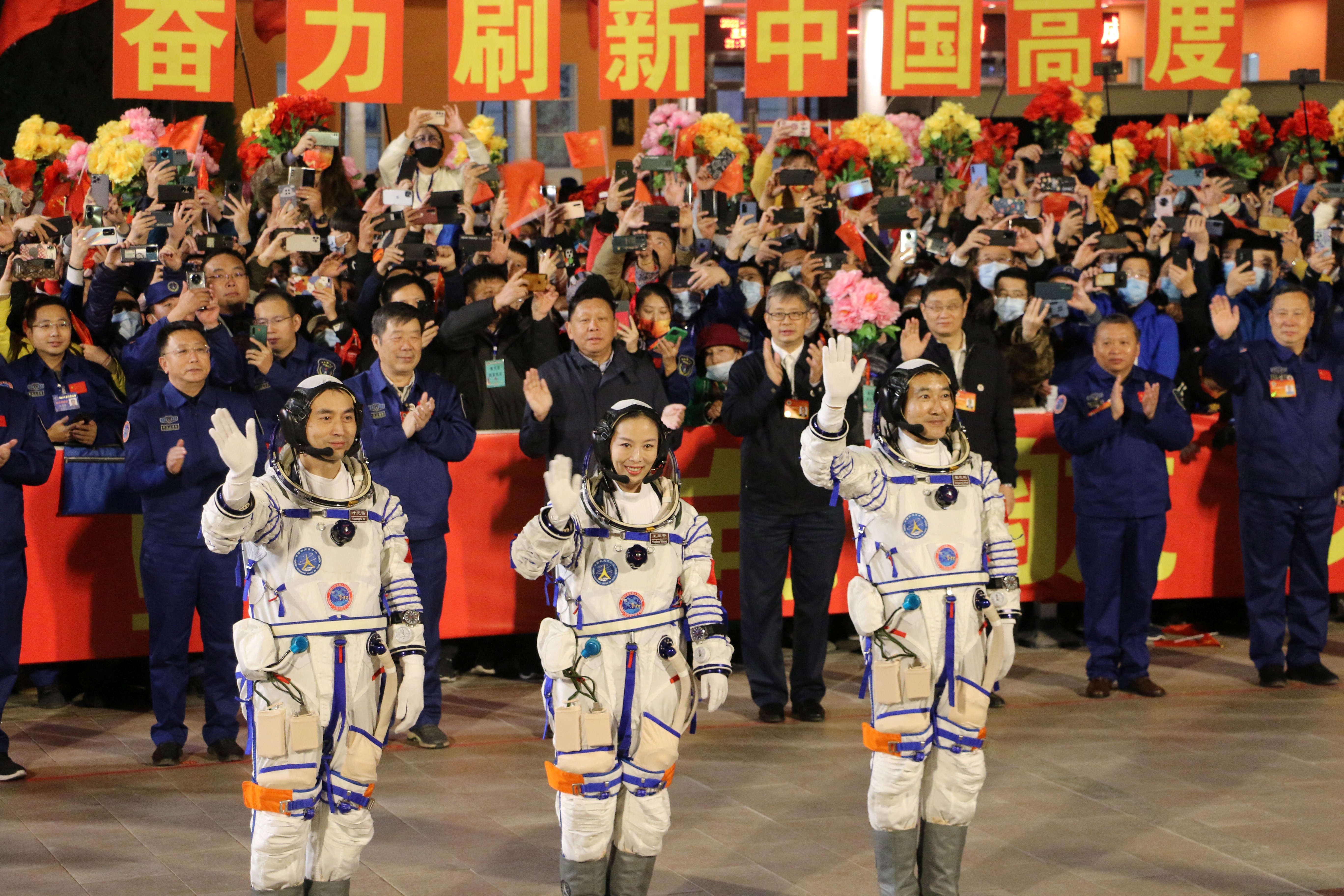 Astronauts Ye Guangfu, Wang Yaping and Zhai Zhigang, wearing space suits wave at a departure ceremony before blasting into space last October.