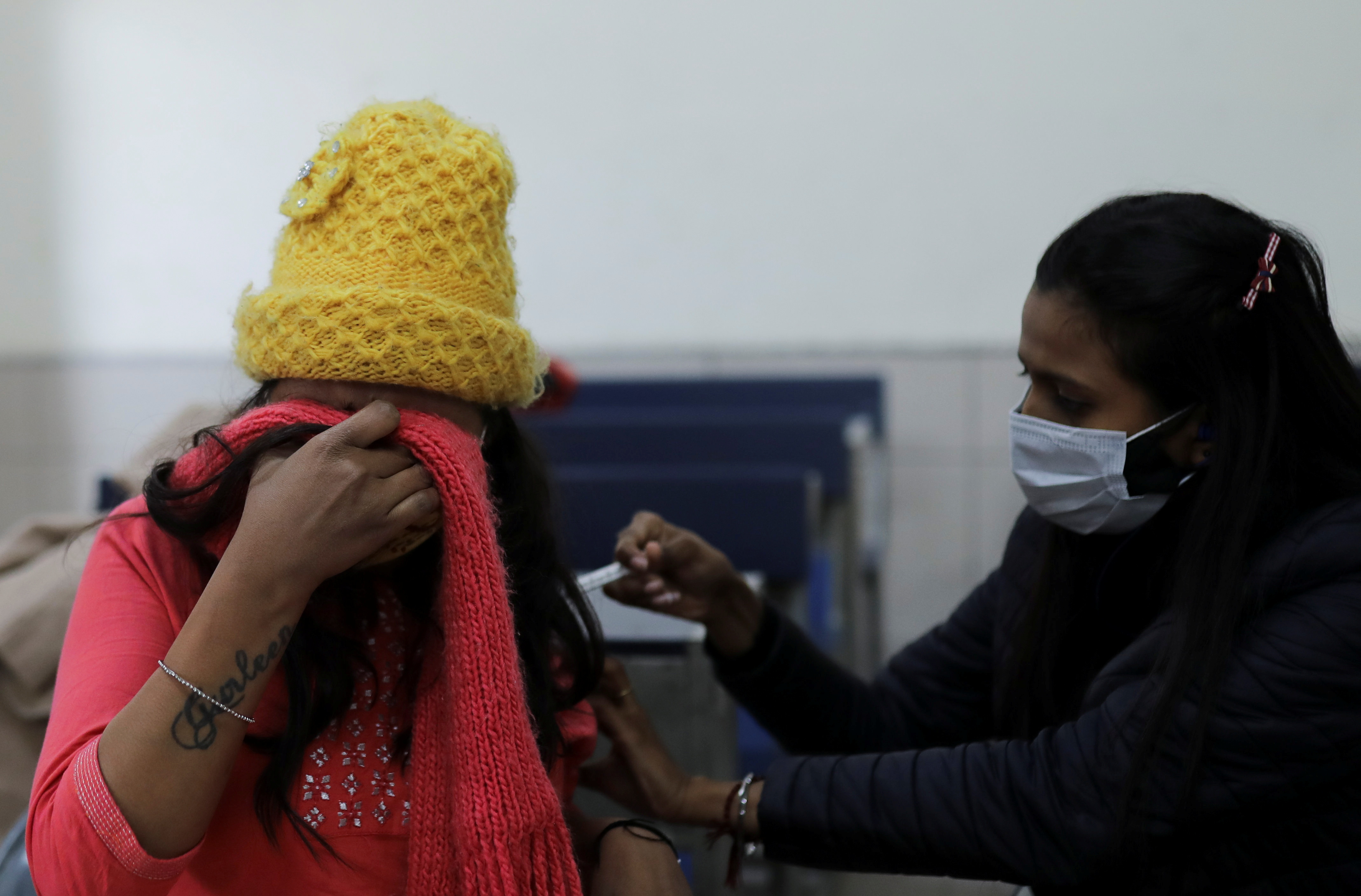 A woman reacts as she receives a dose of the COVISHIELD vaccine in New Delhi, India.