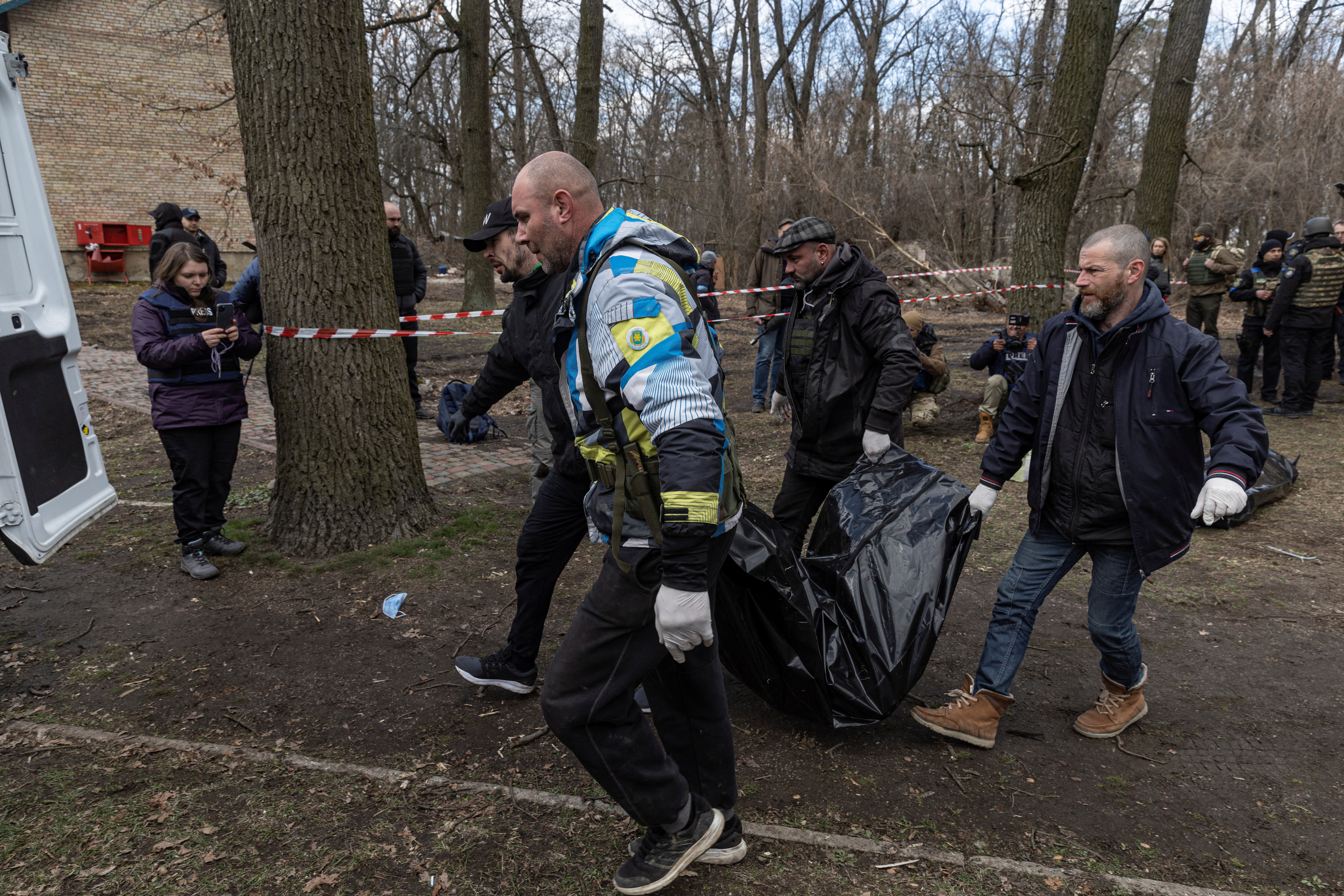 Ukrainian servicemen carry a dead body found in a basement, as Russia's invasion of Ukraine continues, in the town of Bucha, outside Kyiv, Ukraine