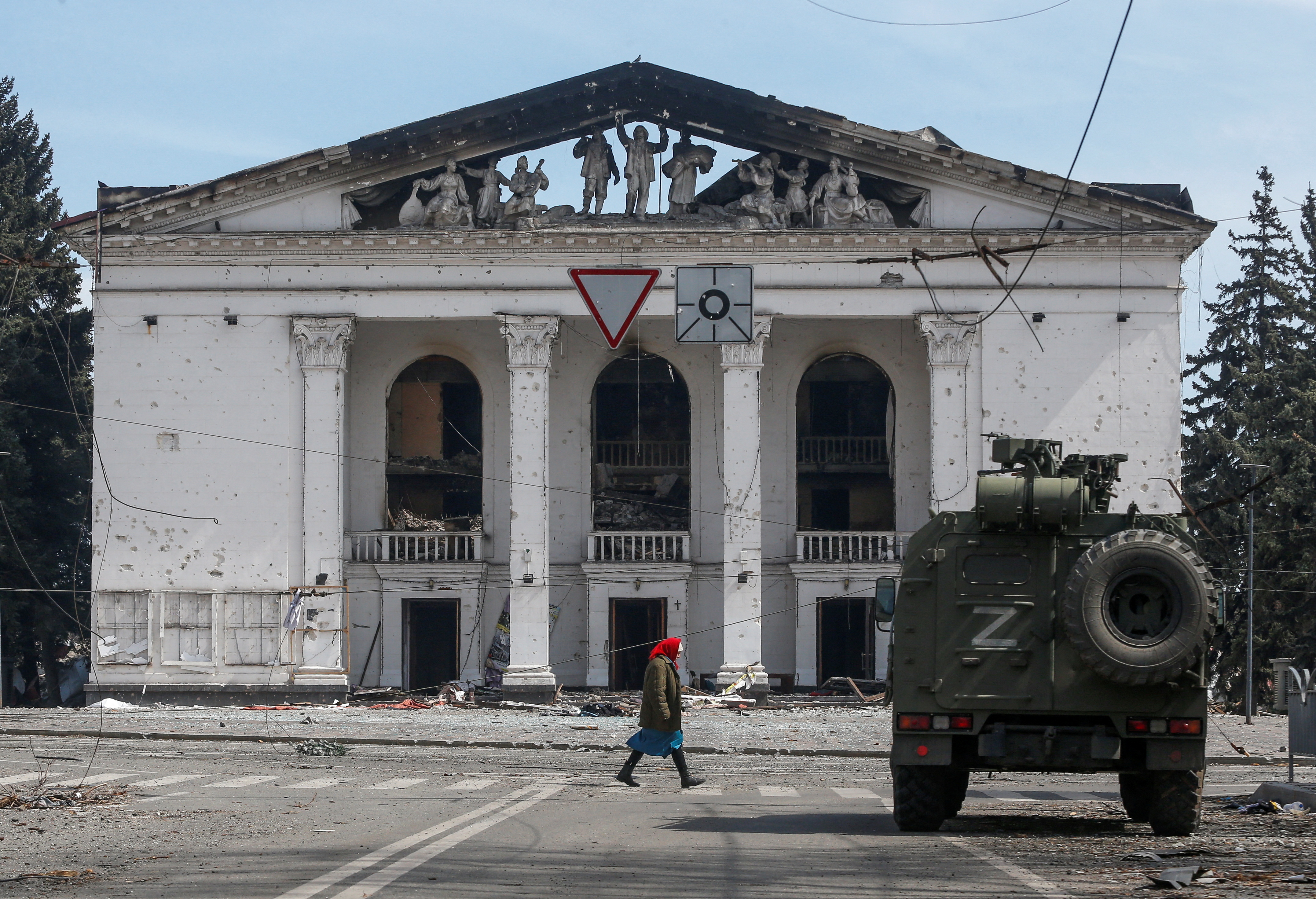 A woman walks next to an armoured vehicle of pro-Russian troops the building of a theatre destroyed in the course of Ukraine-Russia conflict in the southern port city of Mariupol, Ukraine April 10, 2022. REUTERS/Alexander Ermochenko TPX IMAGES OF THE DA
