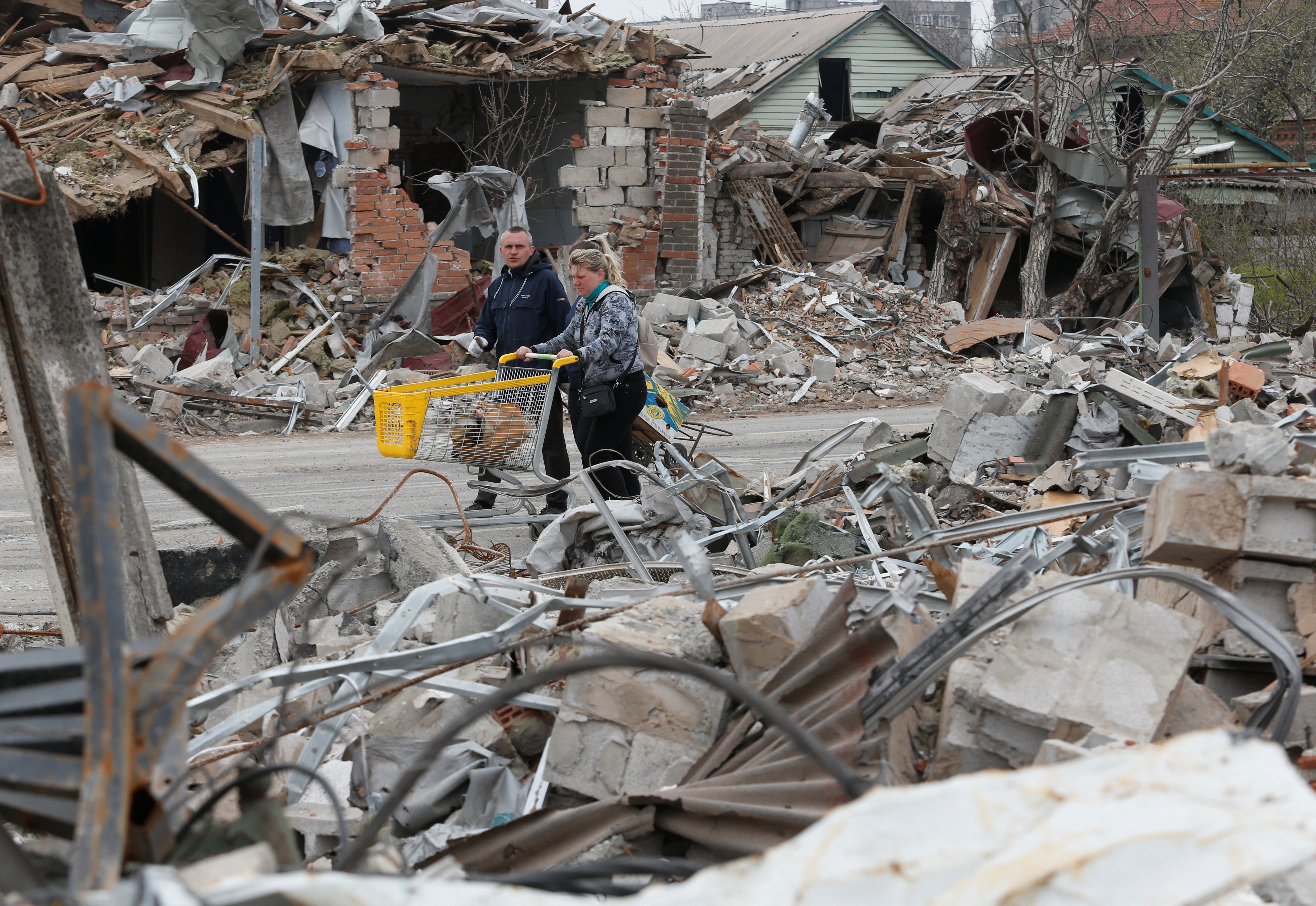 Local residents walk past buildings destroyed during Ukraine-Russia conflict in the southern port city of Mariupol, Ukraine 