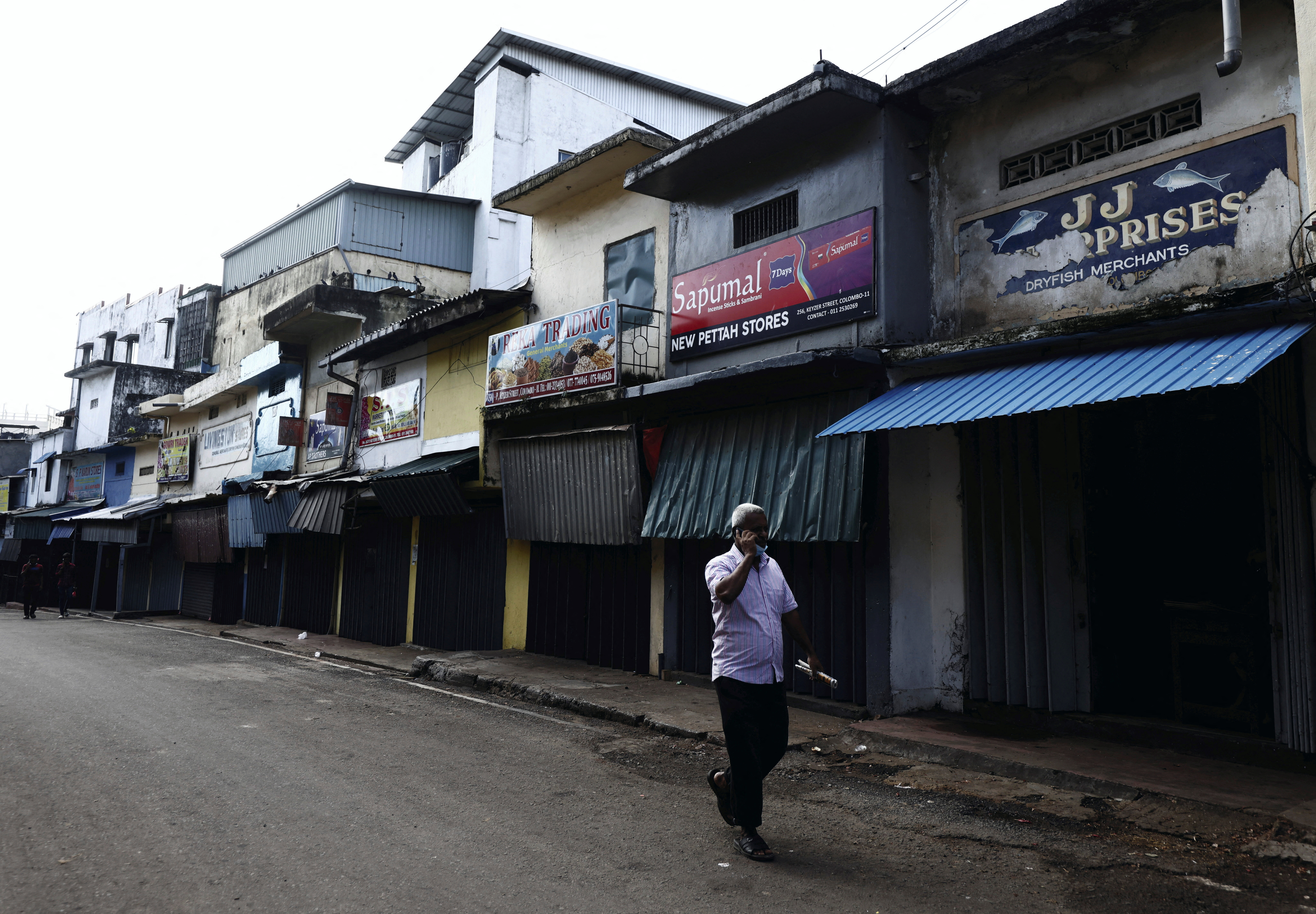 A man walks past a closed essential food store