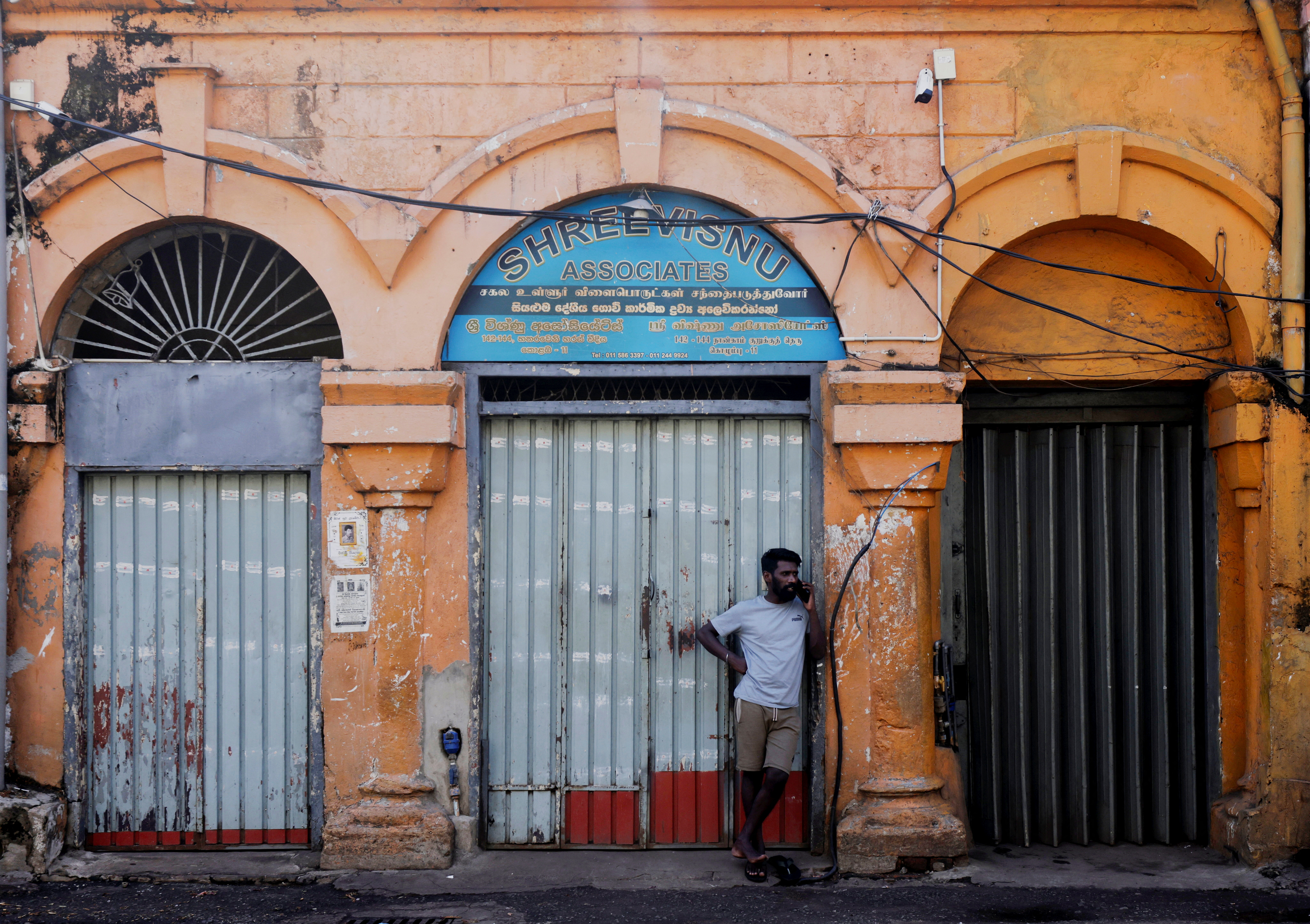 A worker uses a mobile phone in front of a closed essential food store