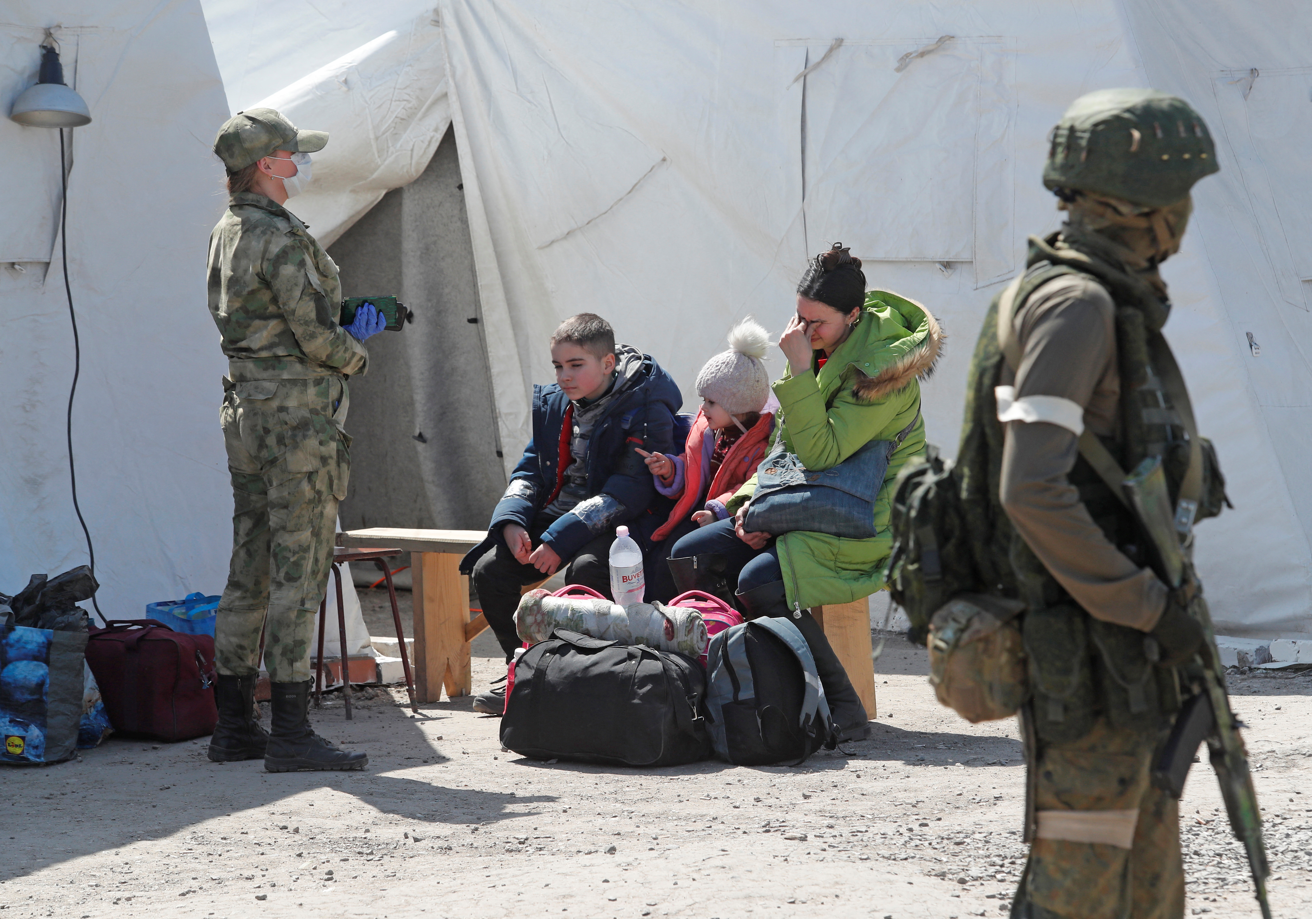 A woman sits with children as evacuees, including civilians who left the area near Azovstal steel plant in Mariupol, arrive at a temporary accommodation centre during Ukraine-Russia conflict in the village of Bezimenne in the Donetsk Region.