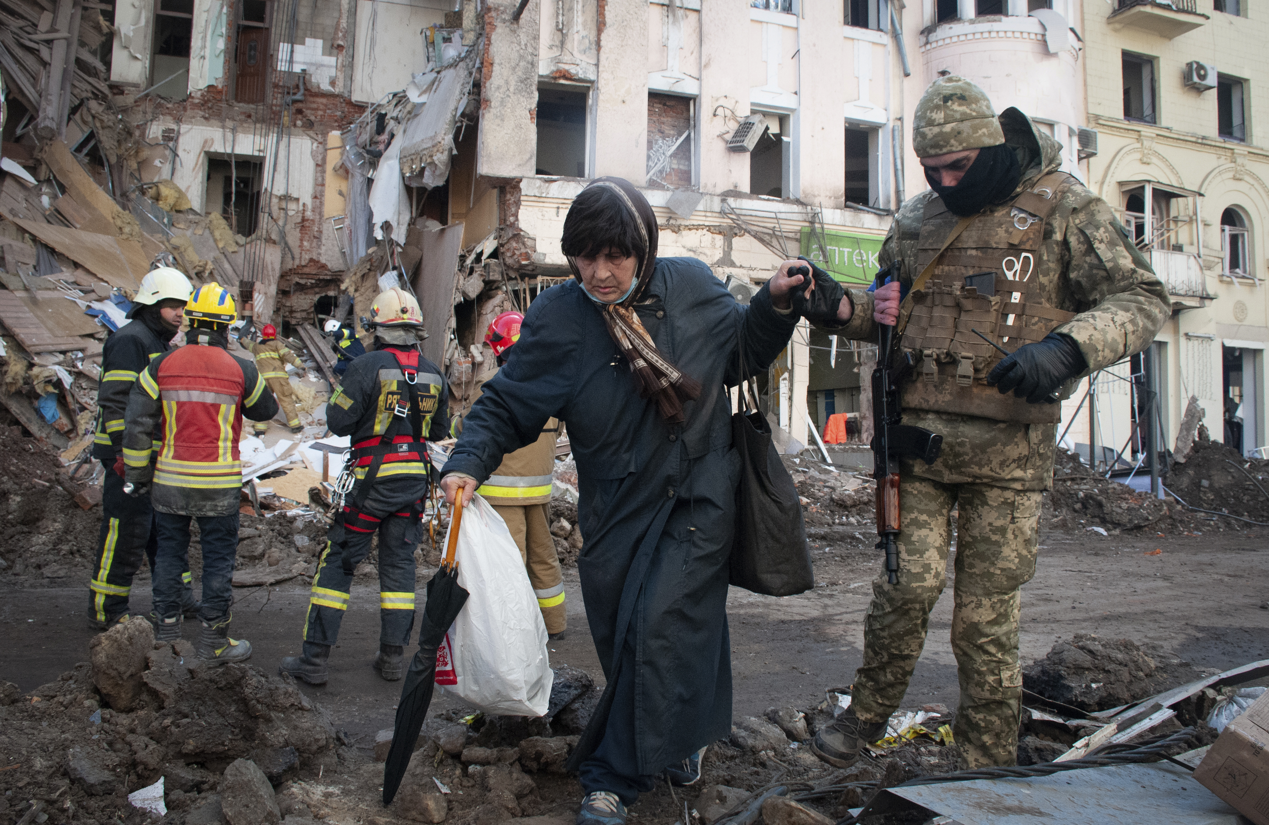 A volunteer of the Ukrainian Territorial Defense Forces assists a woman to cross the street in Kharkiv, Ukraine, Wednesday, March 16, 2022. Both Russia and Ukraine projected optimism ahead of another scheduled round of talks Wednesday, even as Moscow’s forces rained fire on Kyiv and other major cities in a bid to crush the resistance that has frustrated Kremlin hopes for a lightning victory. (AP Photo/Andrew Marienko)