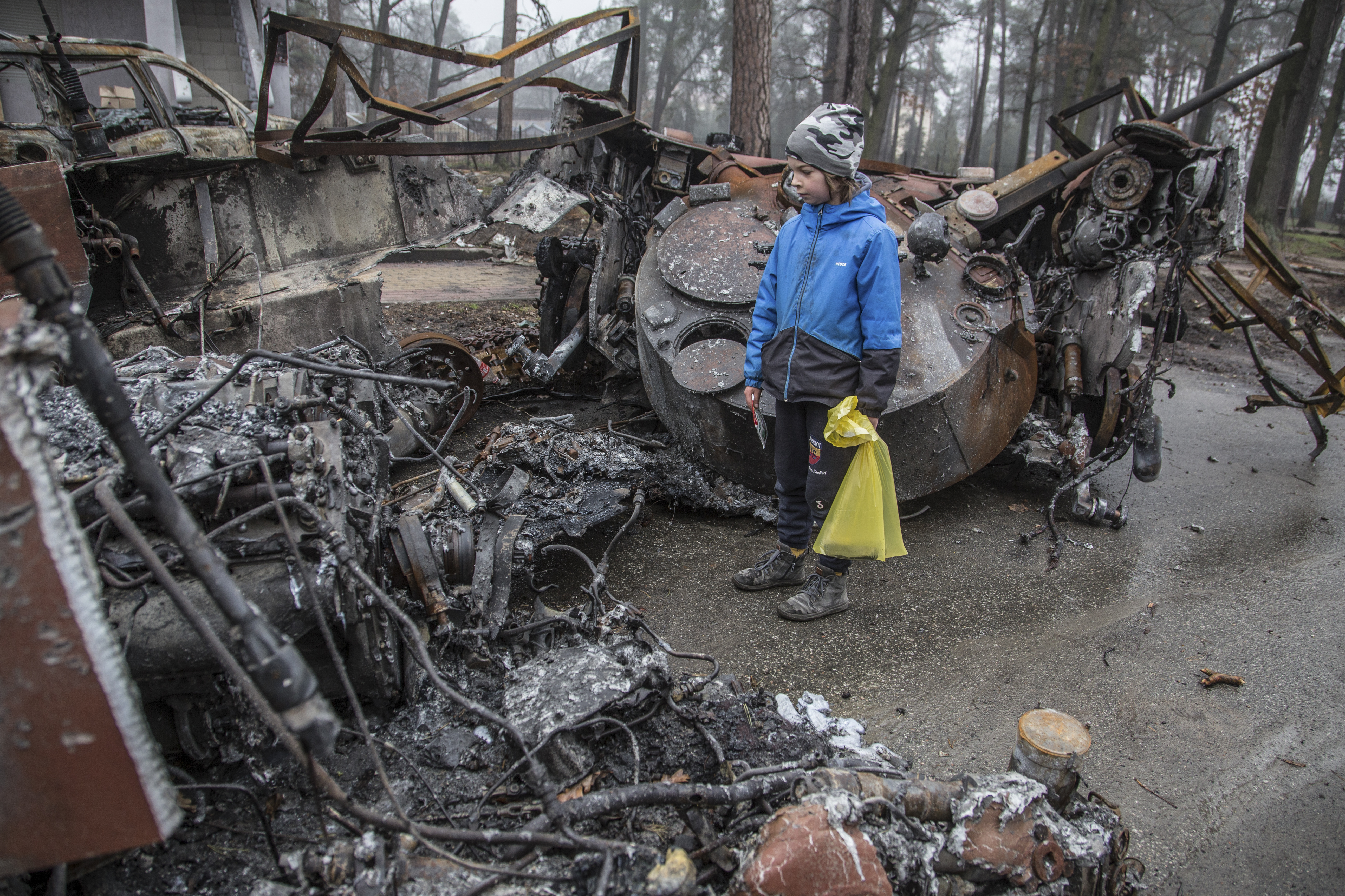 A boy looks at a destroyed Russian tank after recent battles in Bucha