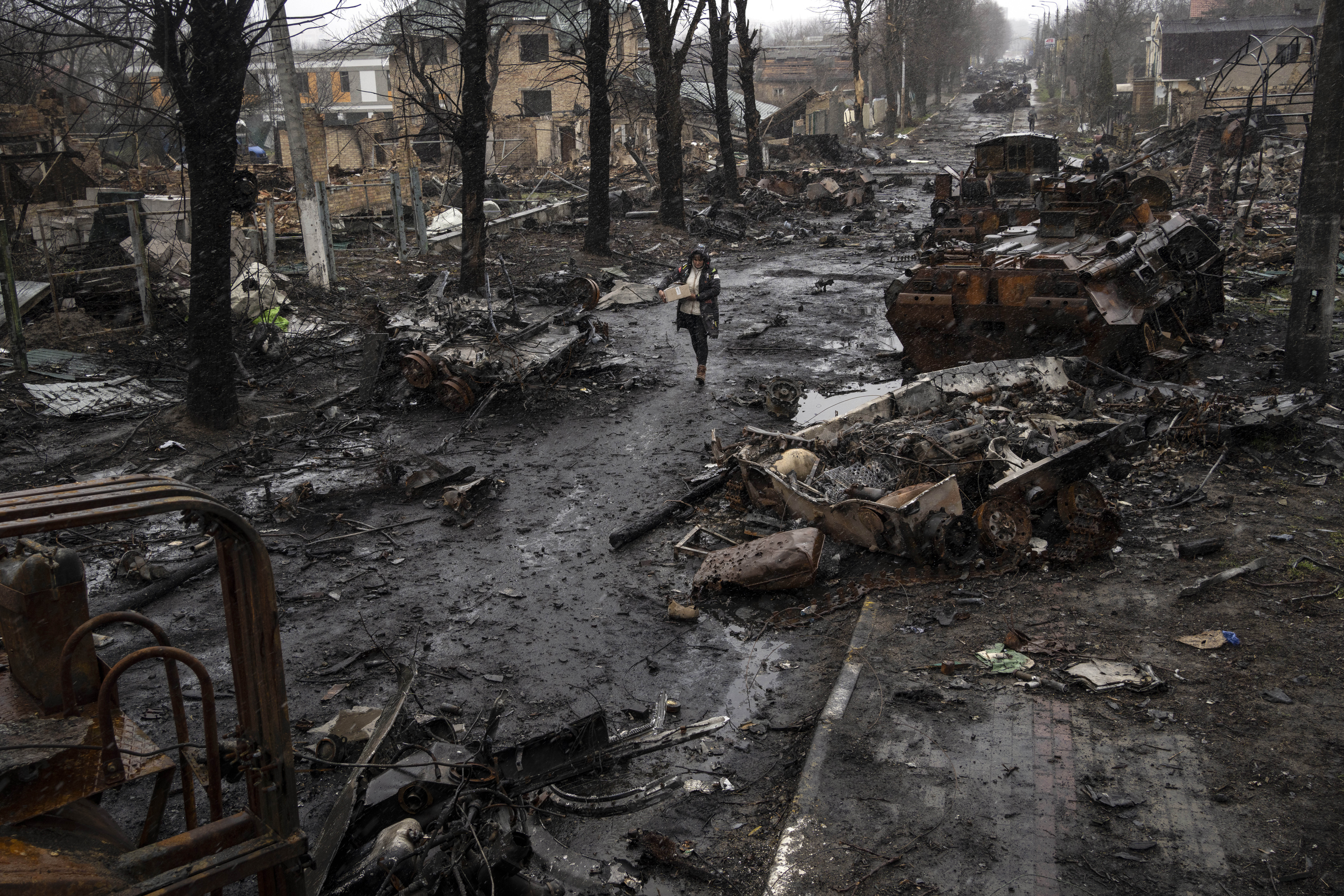 A woman walks amid destroyed Russian tanks in Bucha