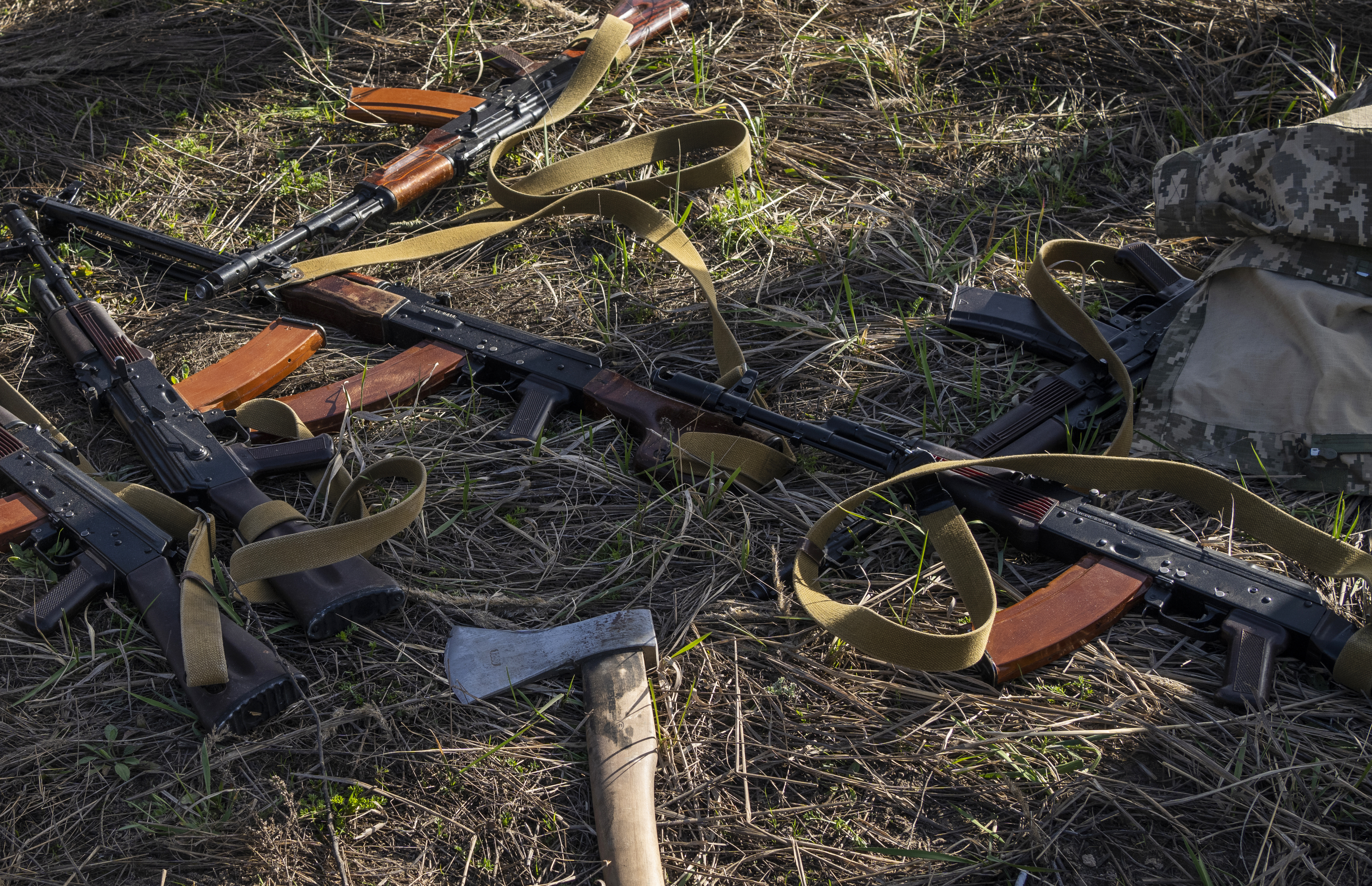 Rifles and an axe lay in a field where Ukrainian soldiers dig a trench in case of another Russian invasion, in Bucha, on the outskirts of Kyiv