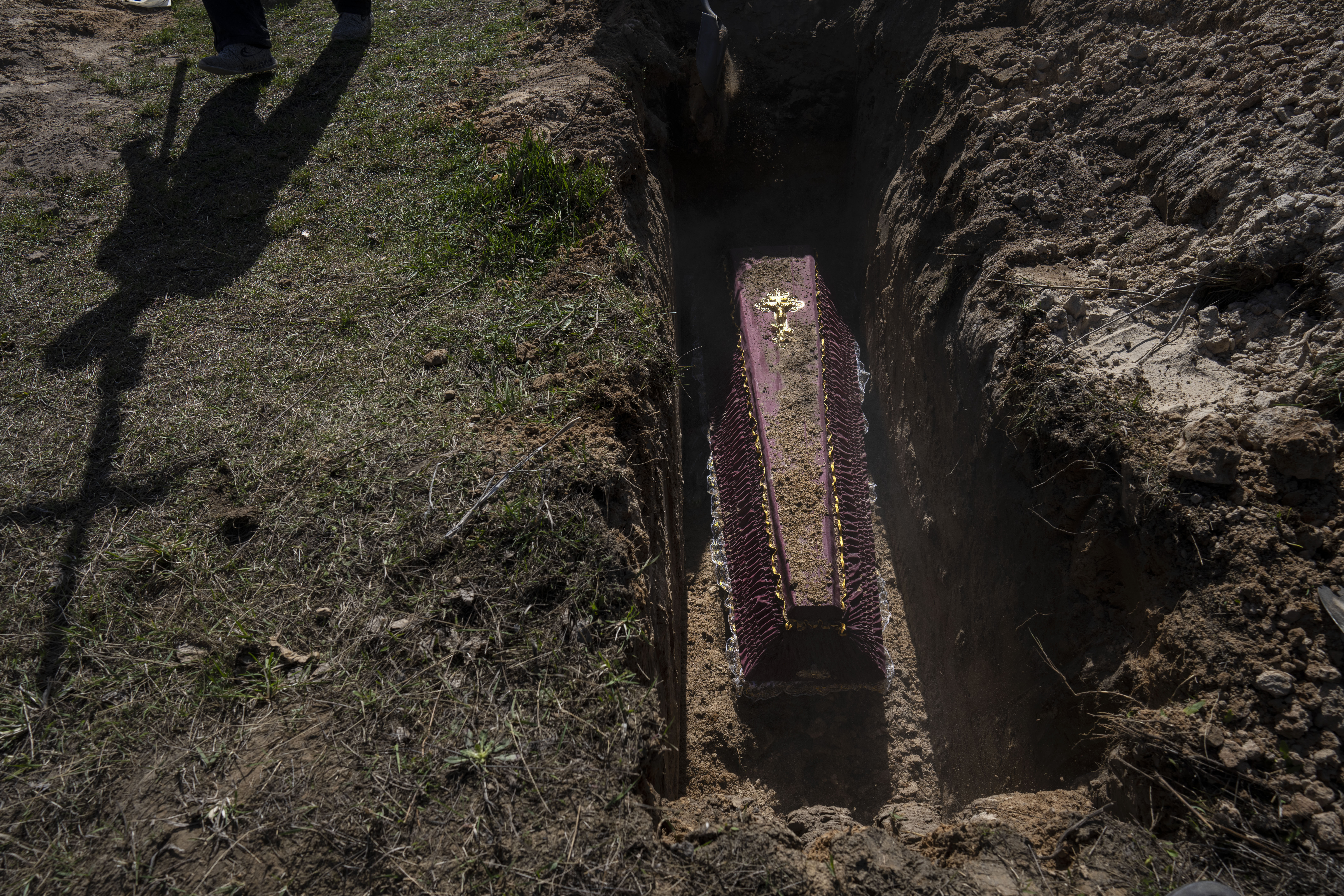 A cemetery worker carries a cross for the tomb of Tetyana Gramushnyak, 75, who was killed by shelling on March 19 while cooking food outside her home in Bucha