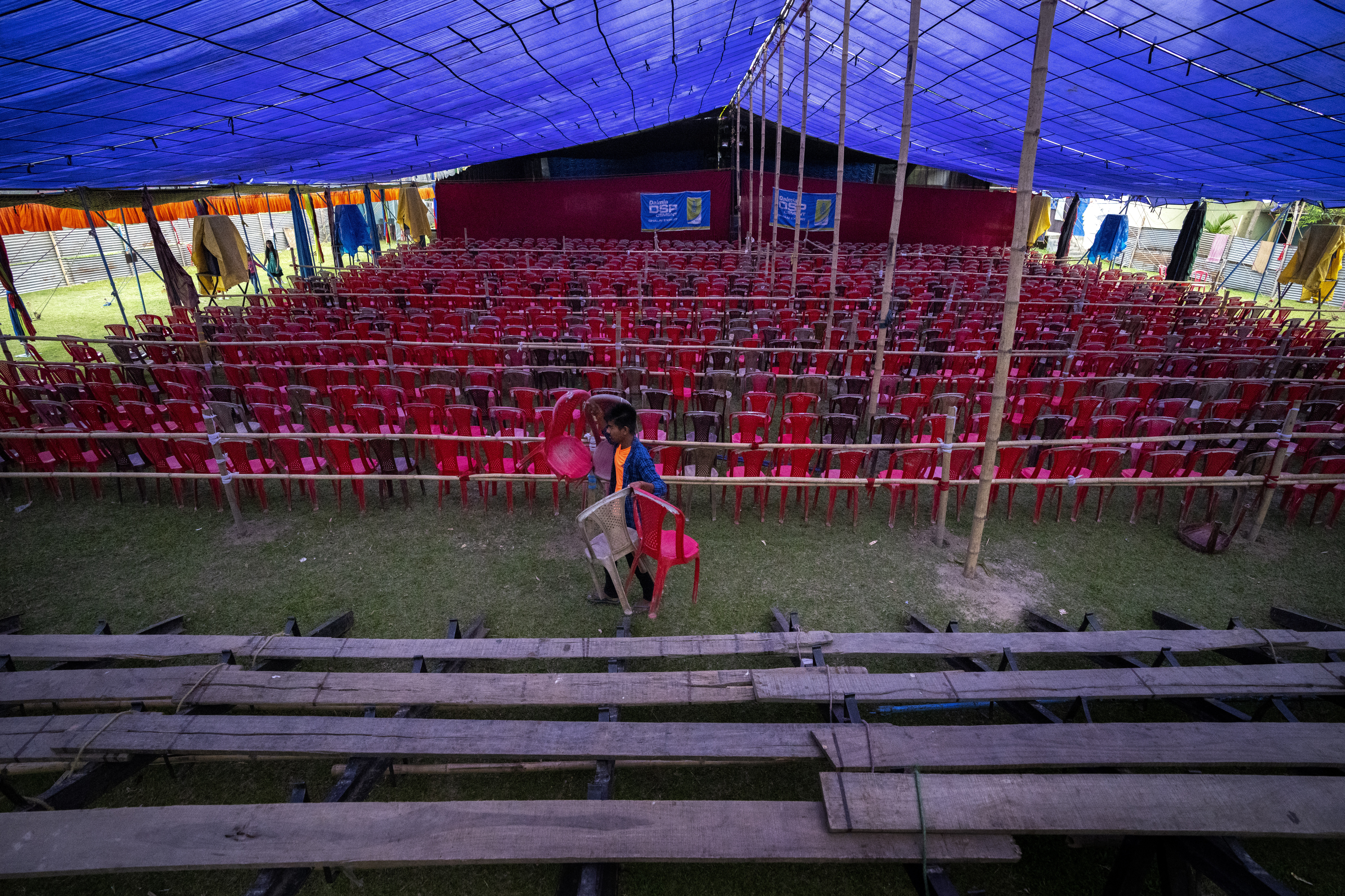 A volunteer arranges chairs inside a tent for a performance by Awahan Theater at Xetali village