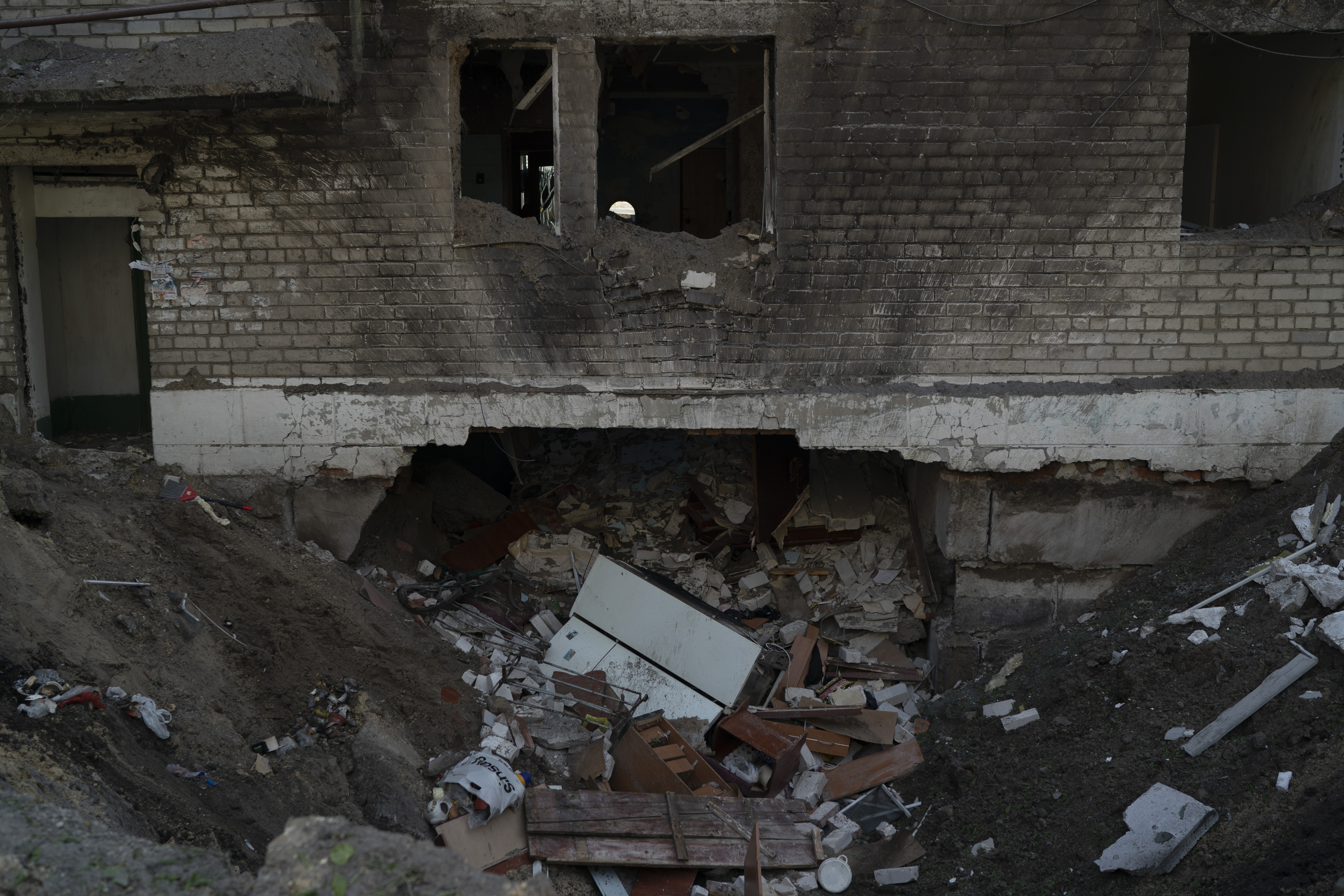 A crater from an explosion is seen next to a heavily damaged apartment and a basement of a residential building that killed, according to the residents, a 8-year-old girl during a Russian attack yesterday, in Lyman, Ukraine