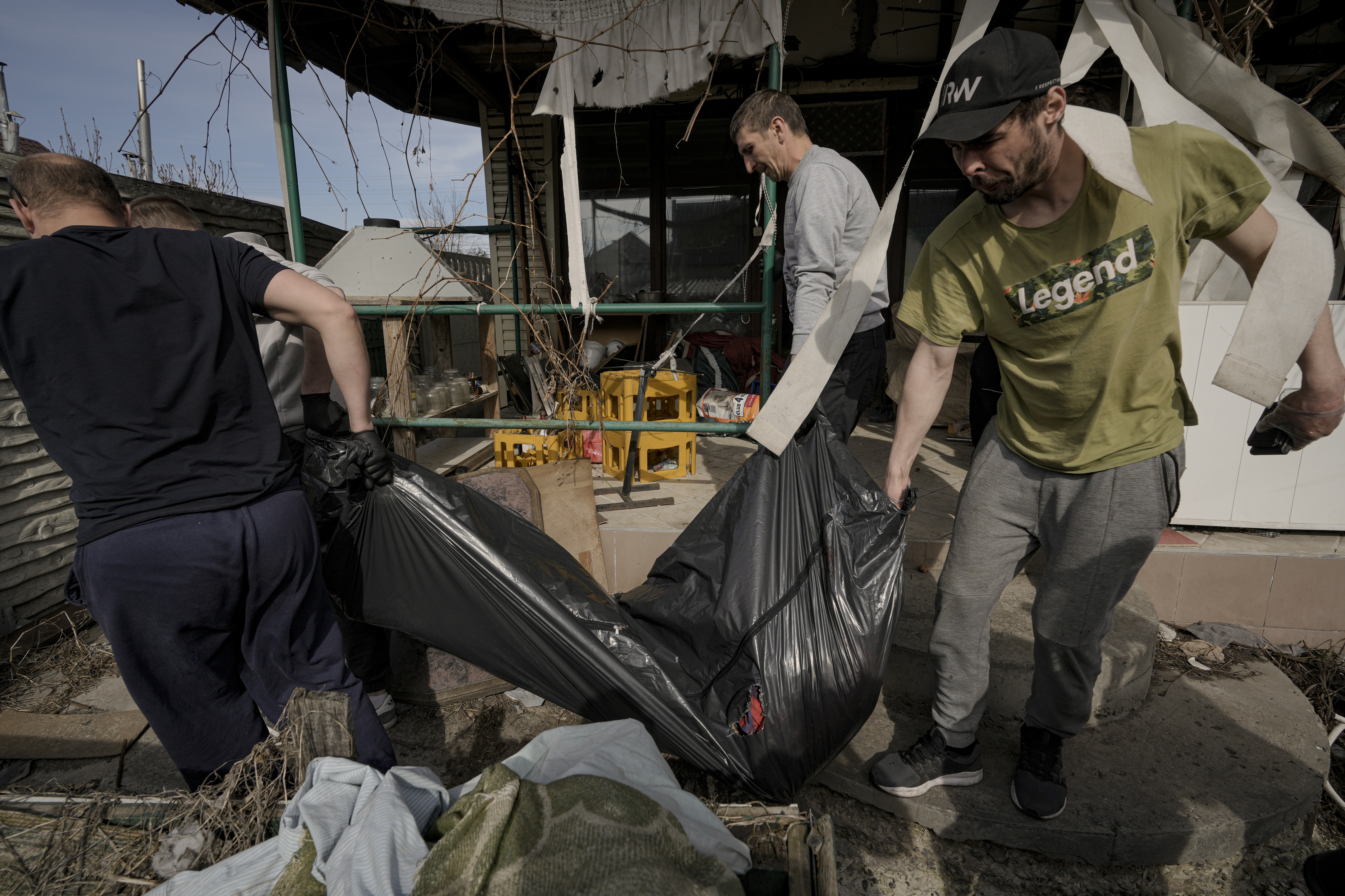Municipal workers remove the body of a man from a house in Bucha.