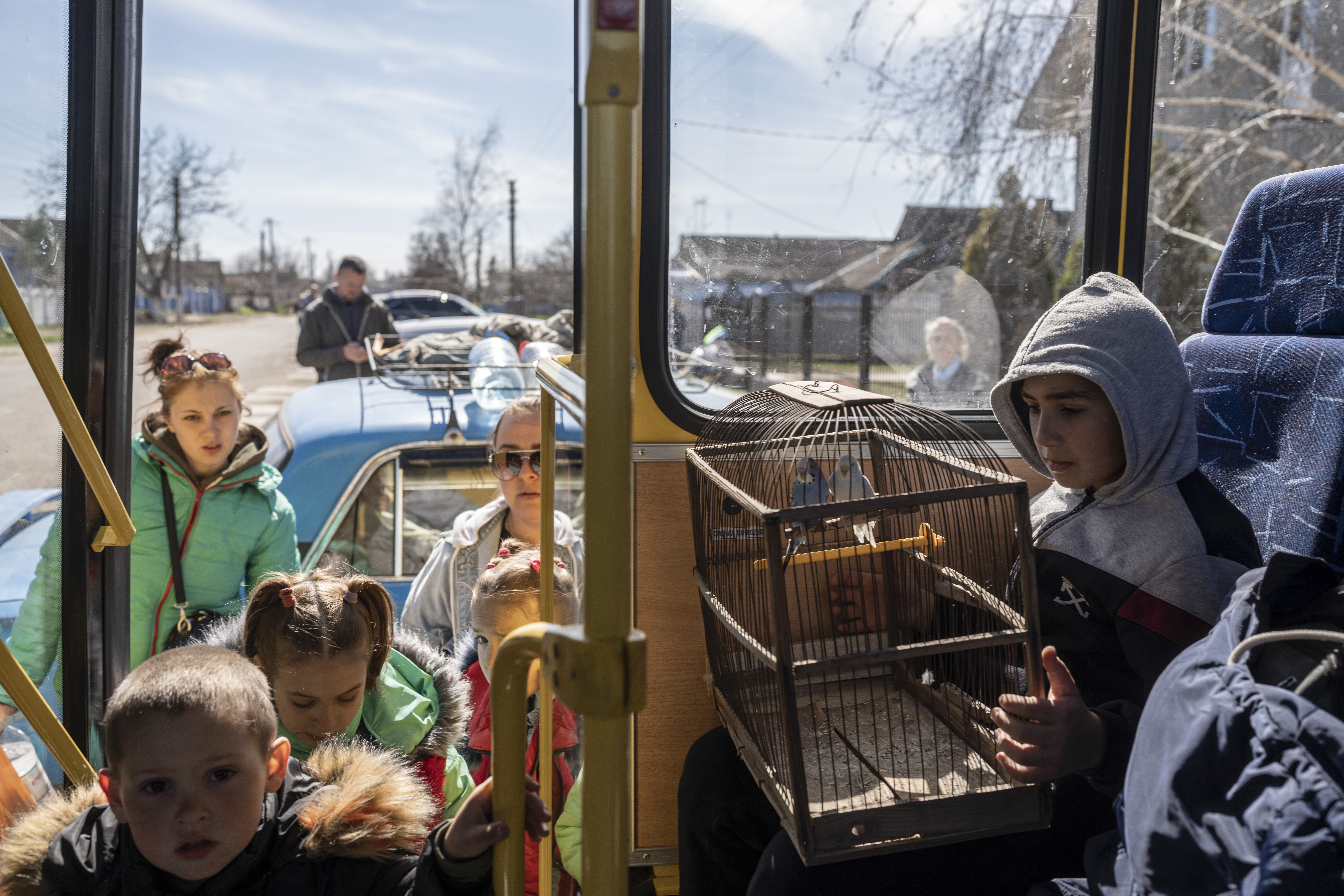 10 year-old Roma holds a cage with two parrots inside a bus leaving from the city of Bashtanka , Mikolaiv district, after he and his family fled from Kherson which is occupied by Russian forces.