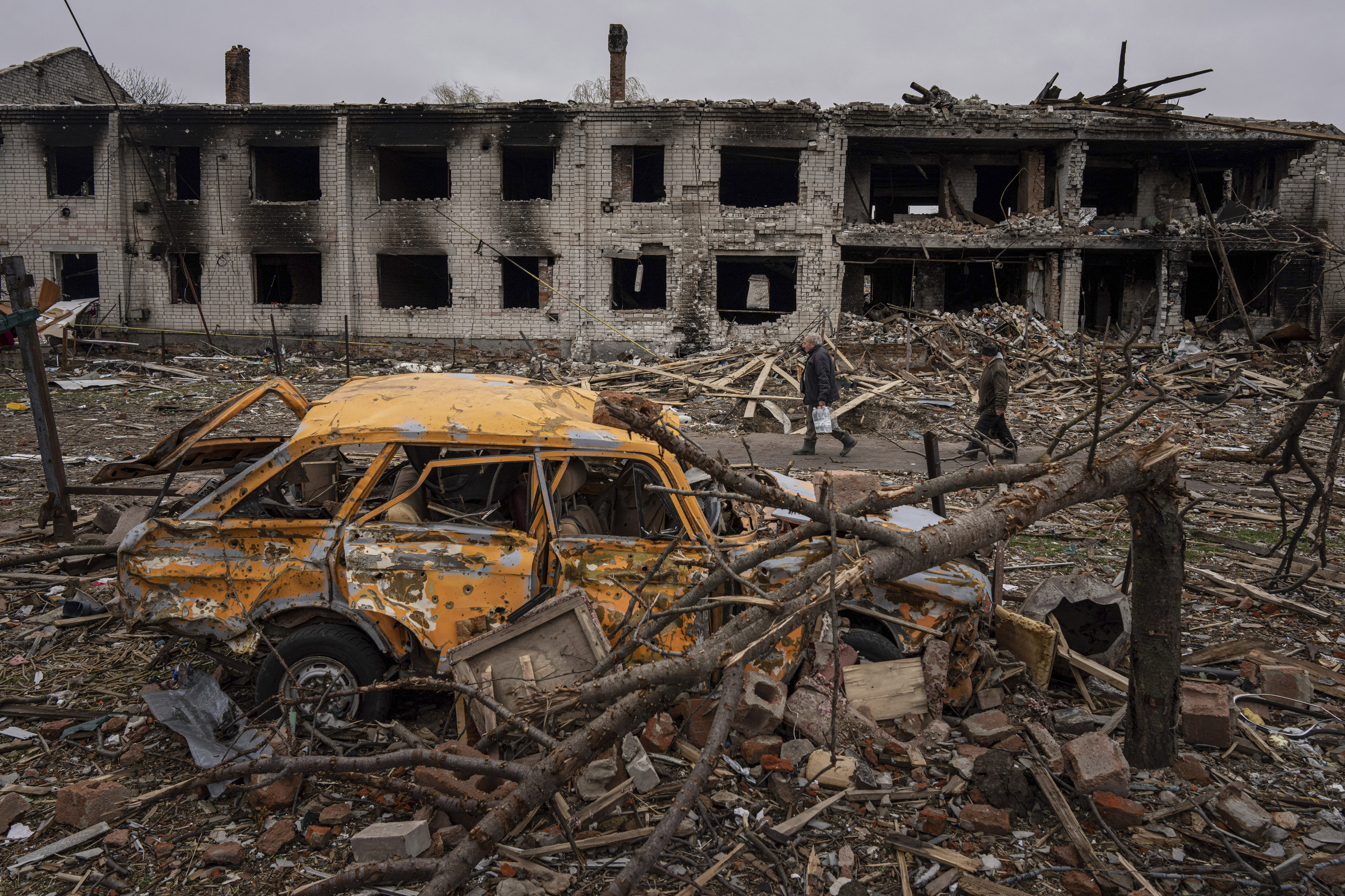 Men walk in a street destroyed by shelling in Chernihiv, Ukraine. 