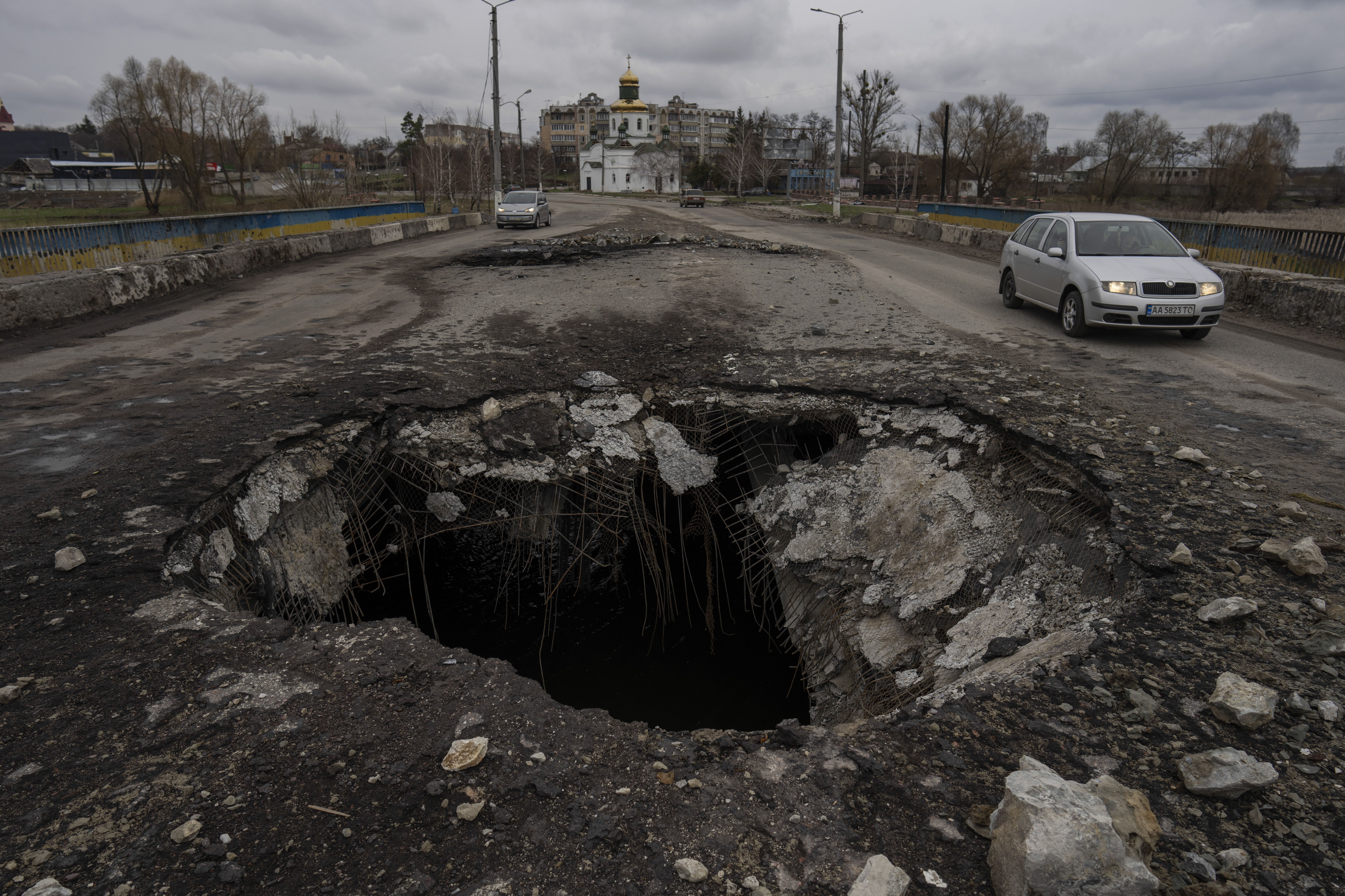 Cars drive near a damaged bridge following Russian attack in the town of Makarov, Kyiv region.