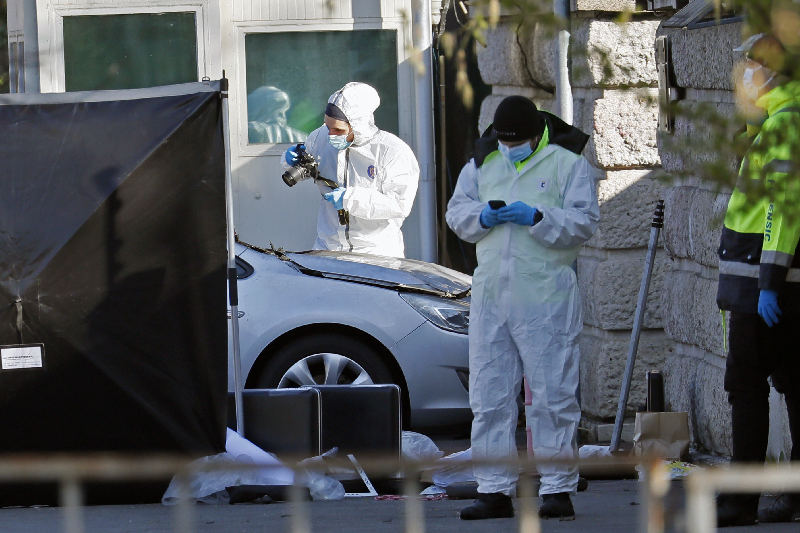 Police collect evidence from around a car that rammed into the gate of the Russian embassy early in the morning in Bucharest