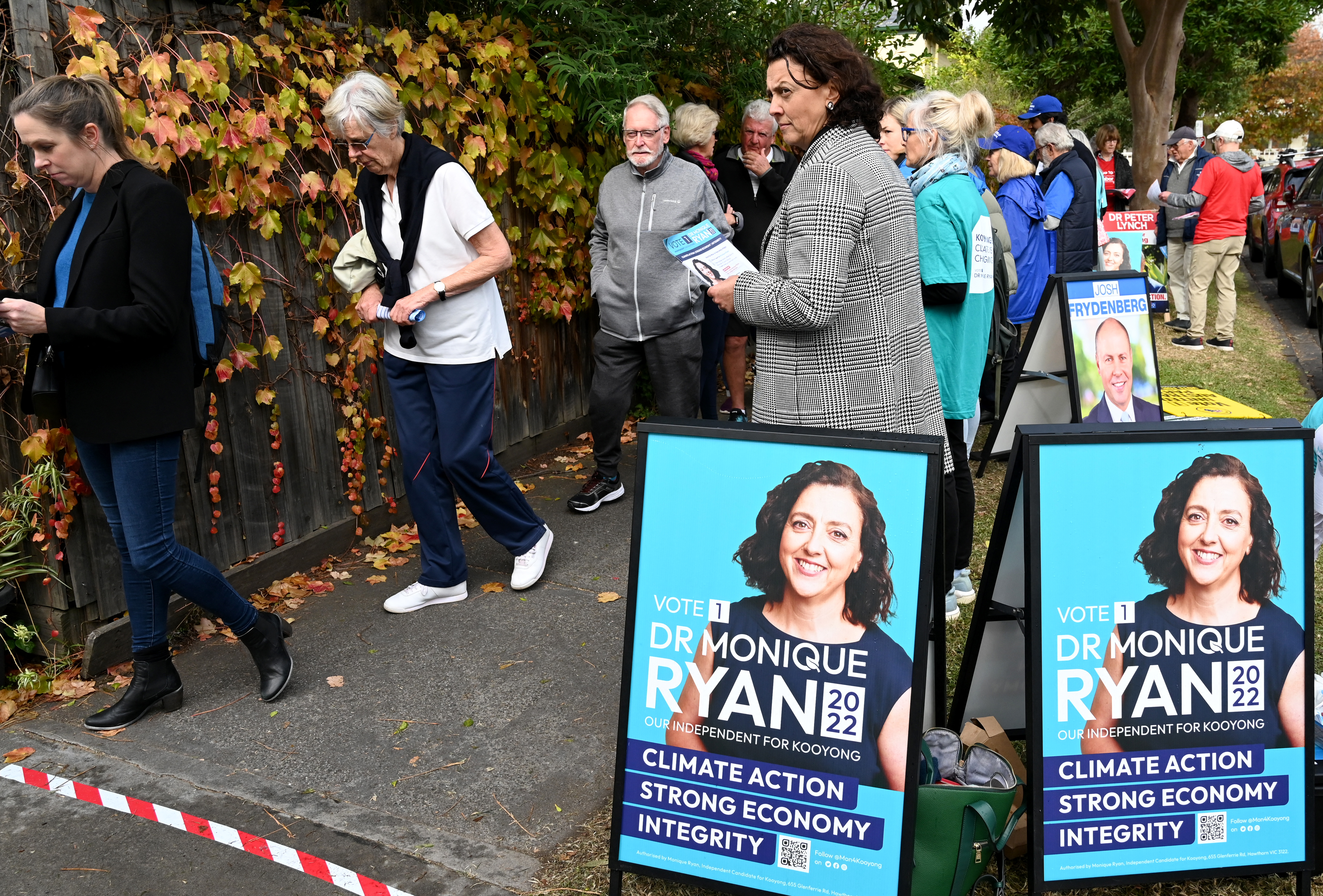 Independent candidate Monique Ryan (C) speaks with a voter on the street outside at a pre-polling centre in Melbourne