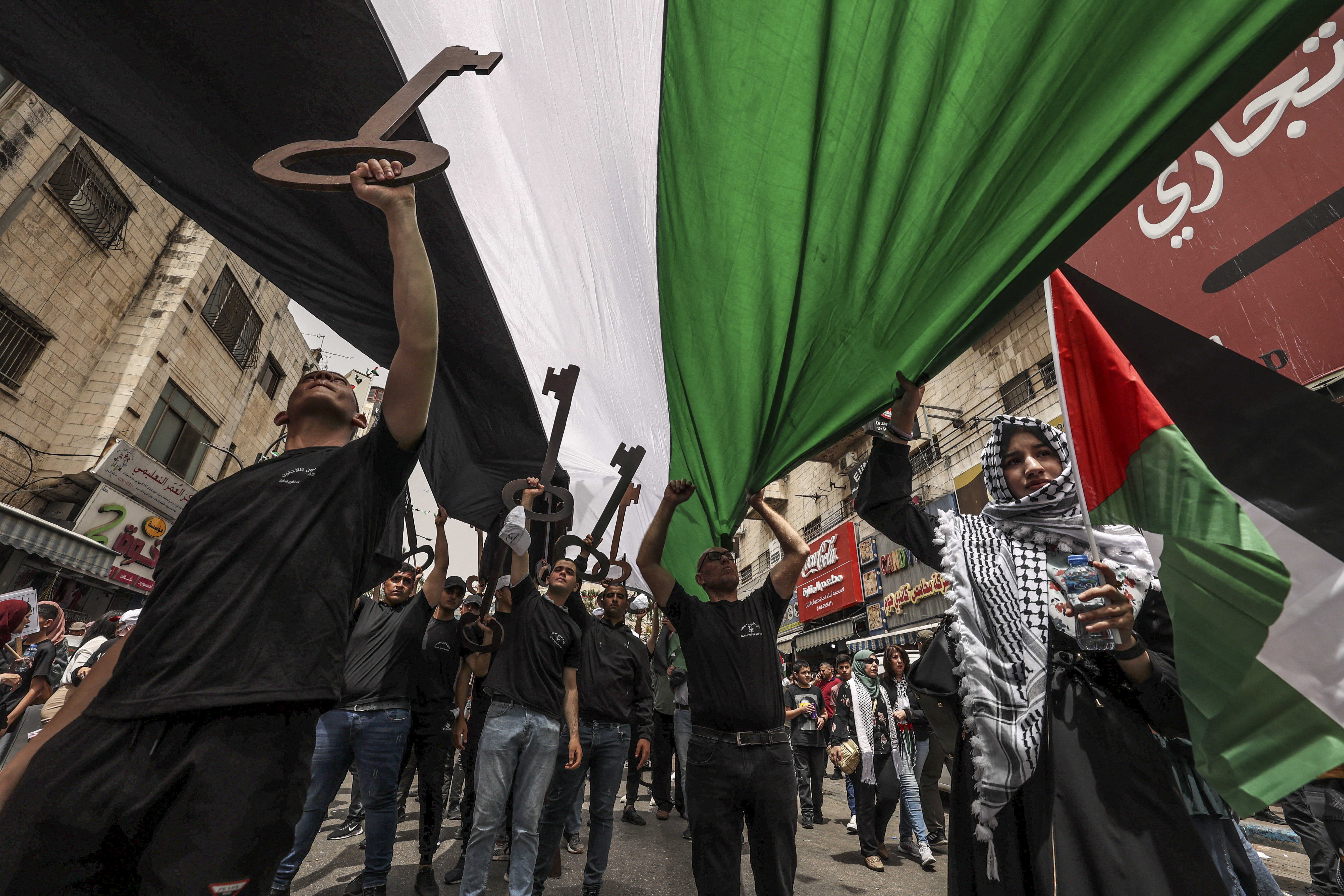 Palestinian wave national flags as they march in a rally marking the 74th anniversary of the "Nakba" or "catastrophe"