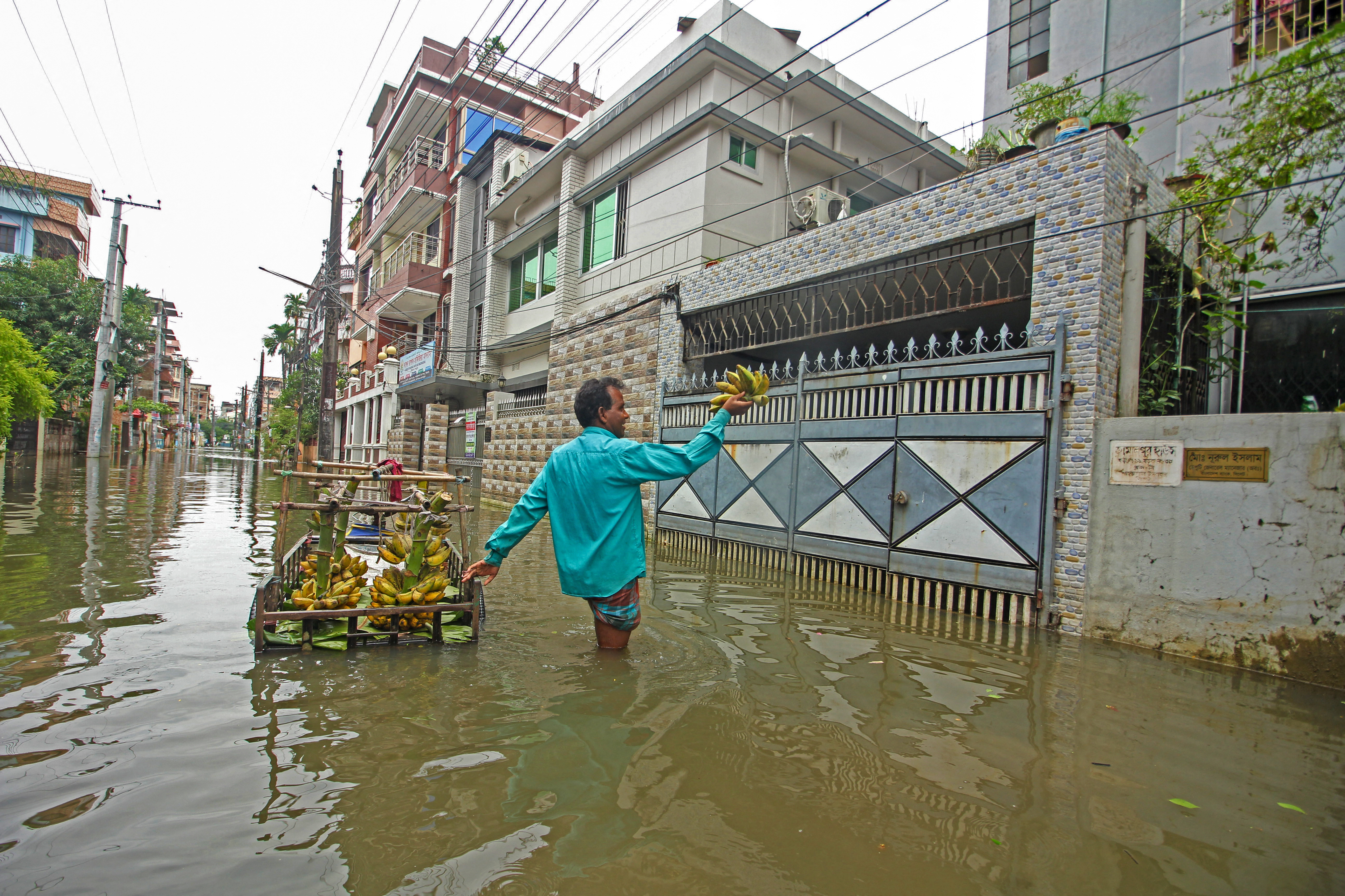 A fruit vendor sells bananas along a flooded street following heavy rains in Sylhet