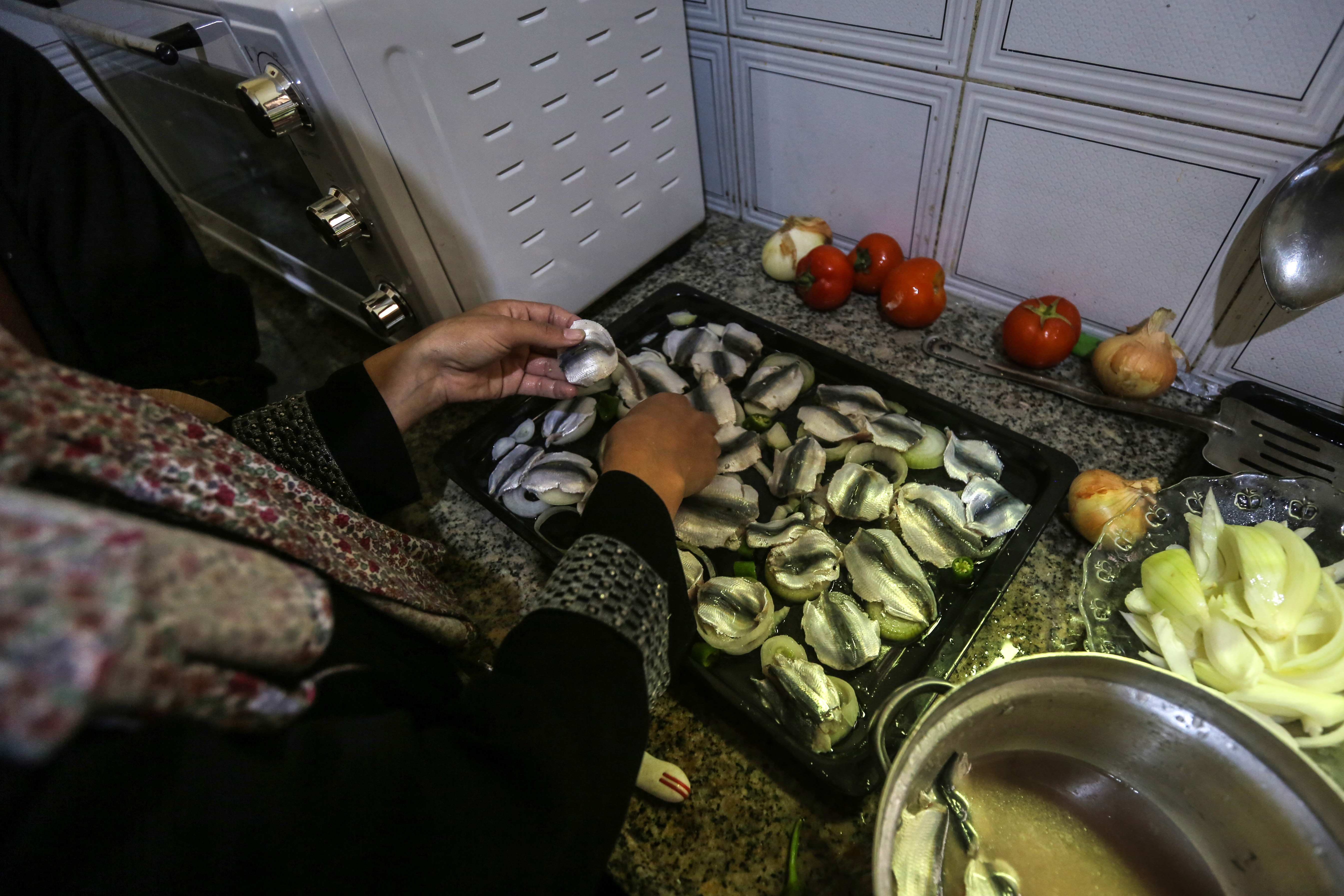 Madelyn's hands are shown layering sardine fillets on top of sliced vegetables