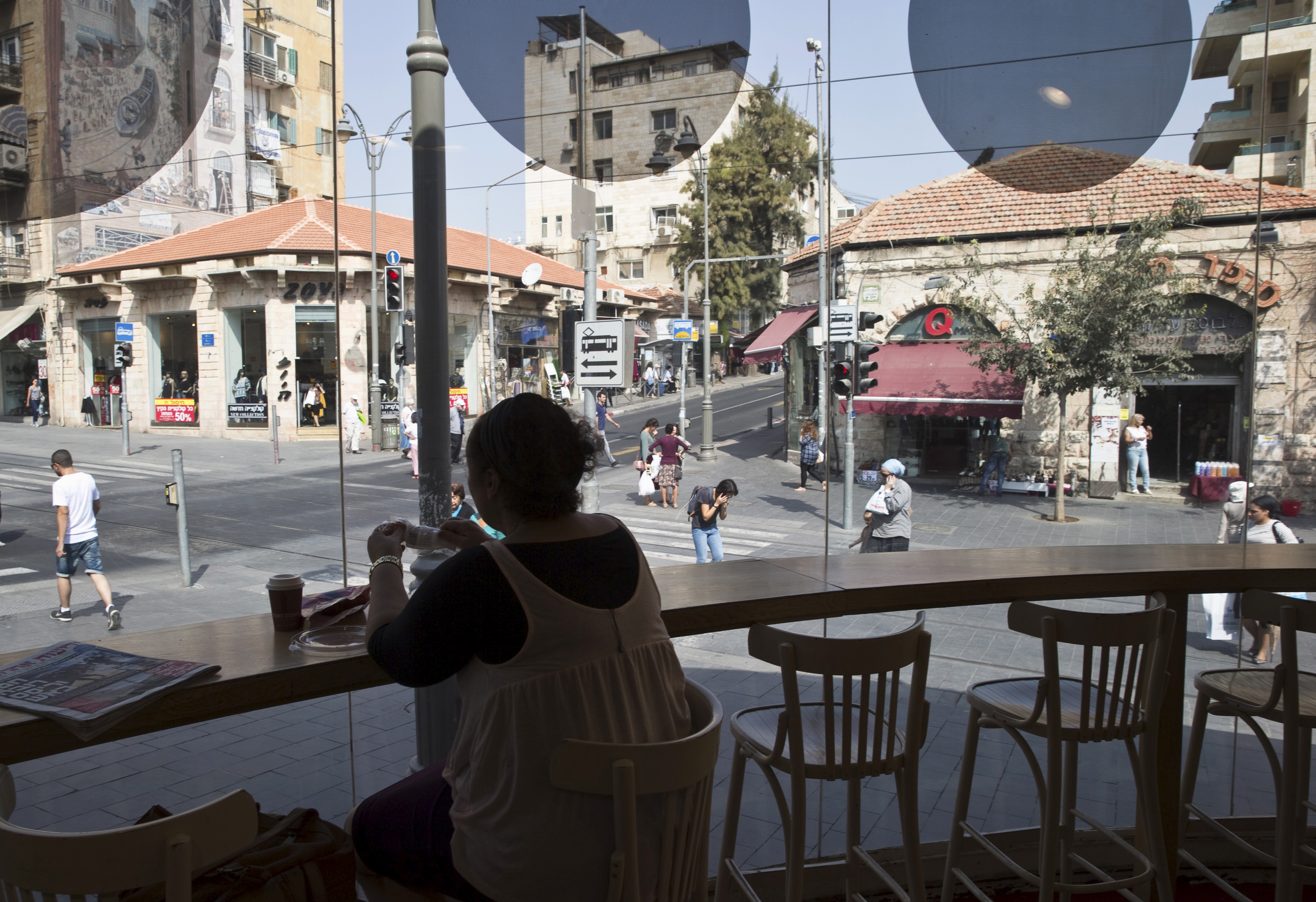 A woman sits at a cafe in the centre of Jerusalem October 19, 2015. A surge in Palestinian attacks in Israel is raising concerns that the weakening economy could eventually be pushed into recession. REUTERS/Ronen Zvulun
