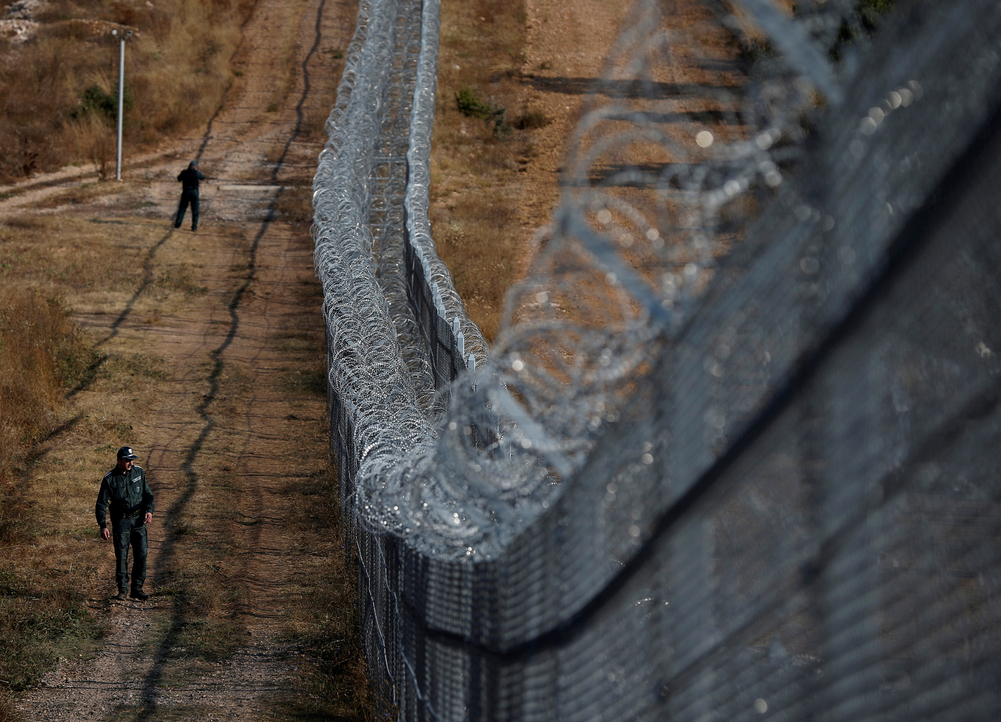 A Bulgarian border policeman walks near the barbed wire fence constructed on the Bulgarian-Turkish border, near Lesovo, Bulgaria