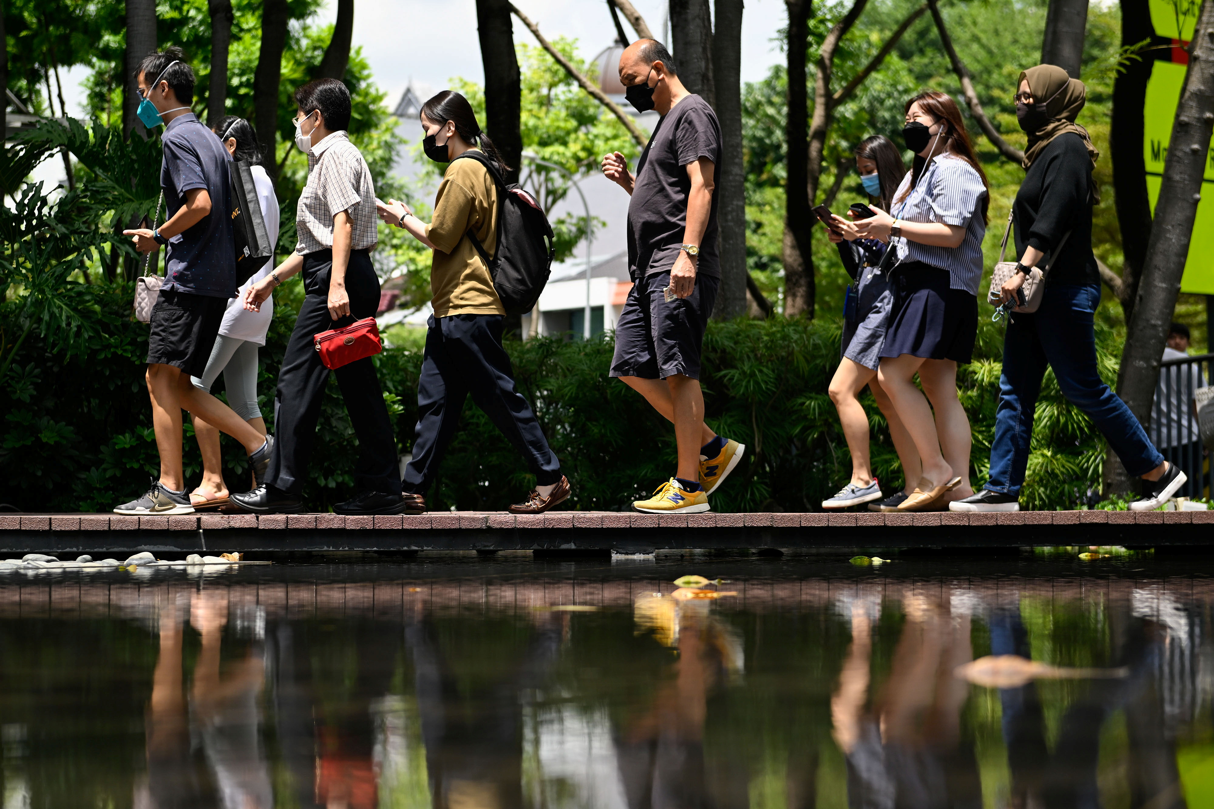People walking along in front of trees on a Singapore street
