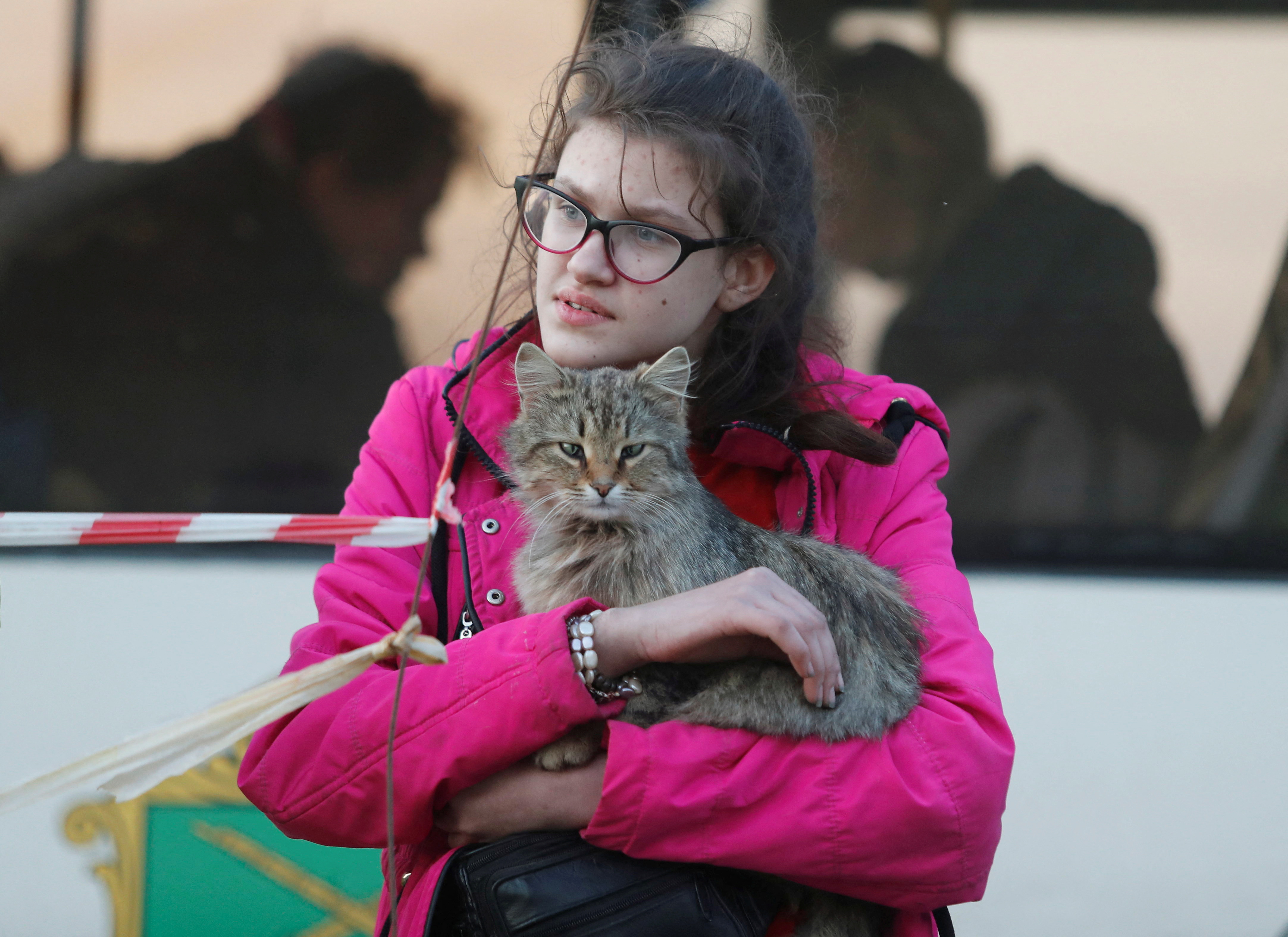 A girl holds a cat next to a bus before departing from a temporary accommodation centre for evacuees during Ukraine-Russia conflict in the village of Bezimenne in the Donetsk Region, Ukraine May 1, 2022. REUTERS/Alexander Ermochenko