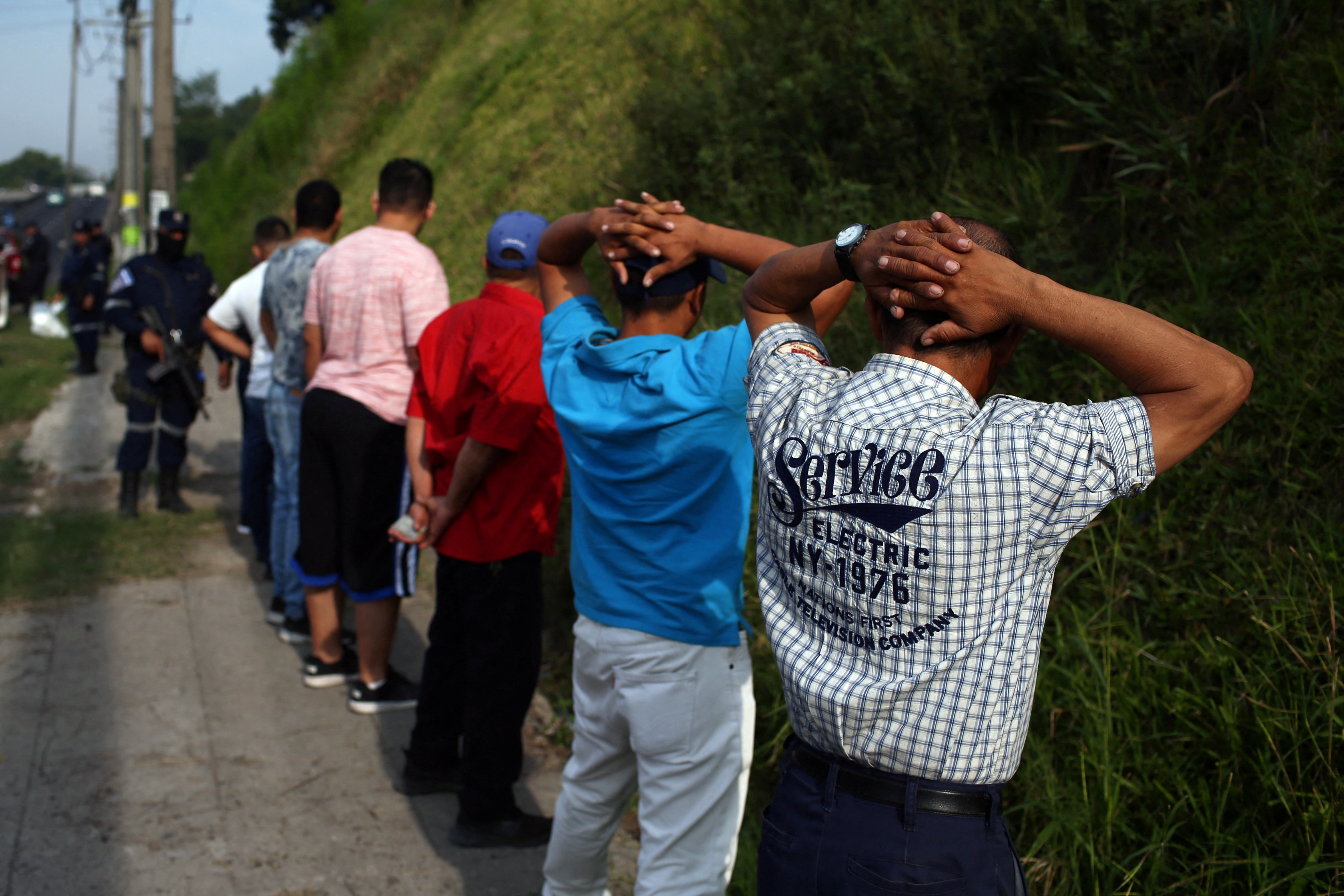 Bus passengers wait to be searched by police at a checkpoint