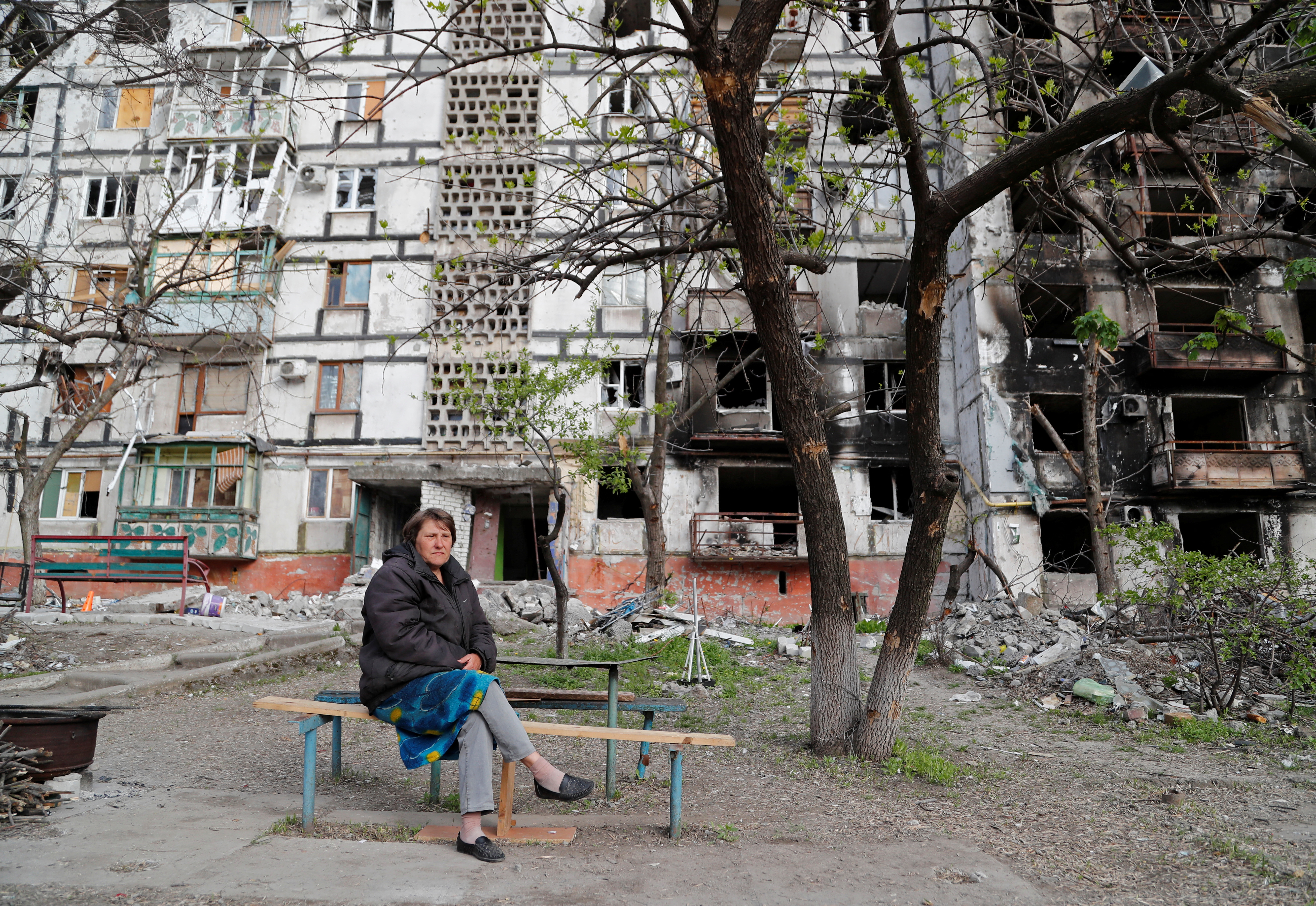Local resident Tatiana Bushlanova, 64, sits on a bench near an apartment building heavily damaged during Ukraine-Russia conflict in the southern port city of Mariupol, Ukraine May 2, 2022. REUTERS/Alexander Ermochenko
