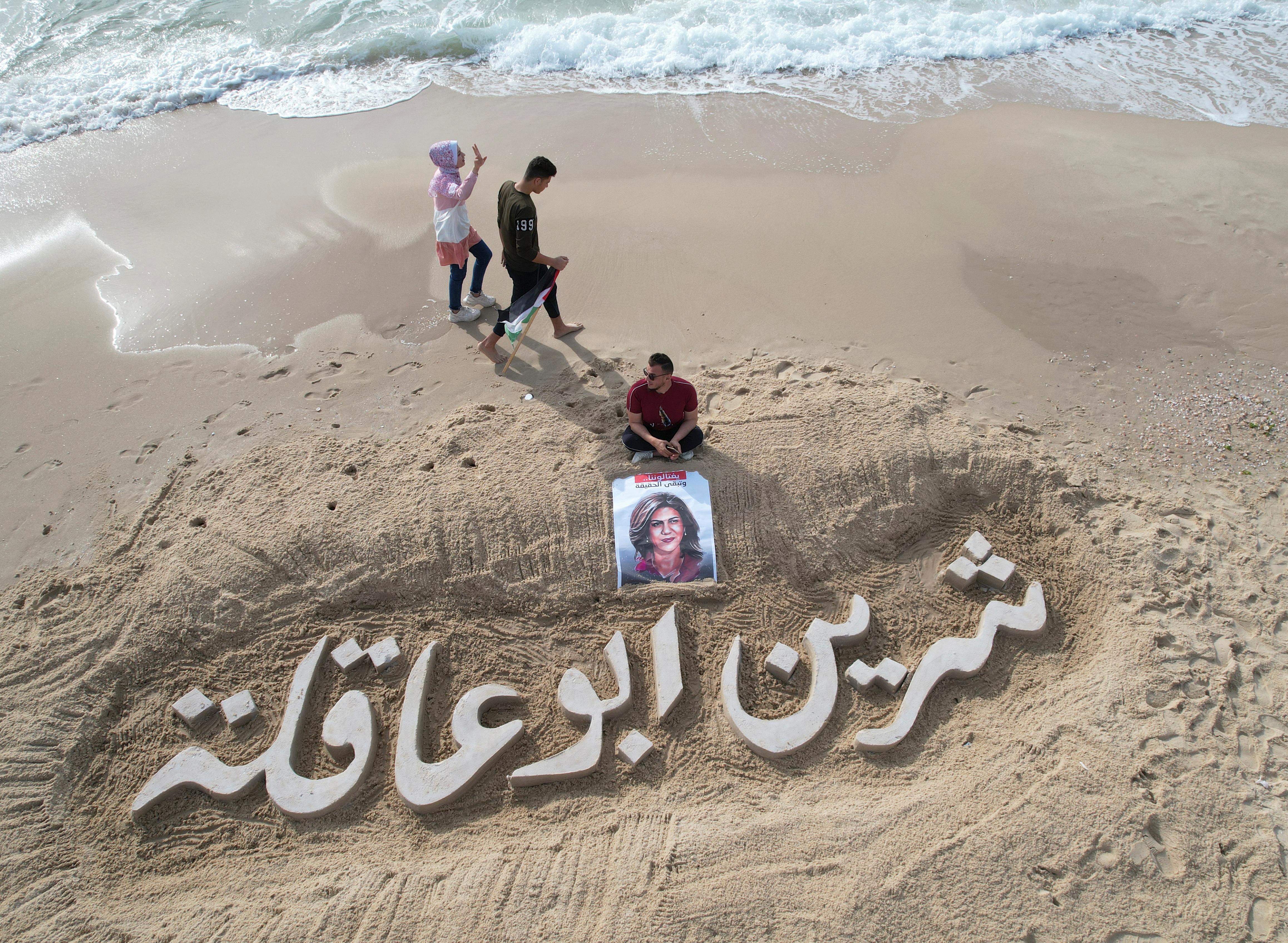 A sand sculpture reads 'Shireen Abu Akleh'